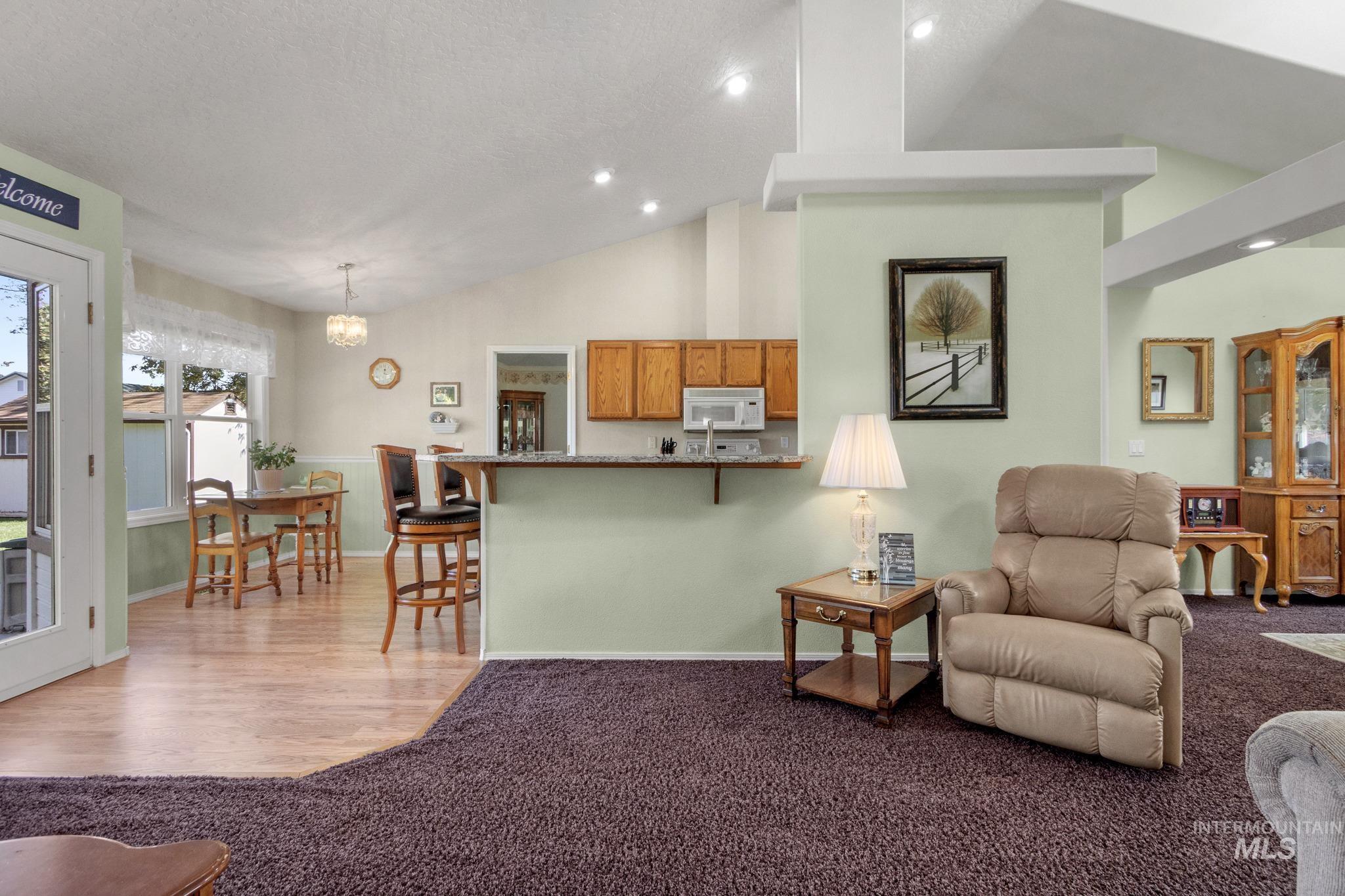 Living room with light carpet, recessed lighting, a chandelier, light wood finished floors, and high vaulted ceiling