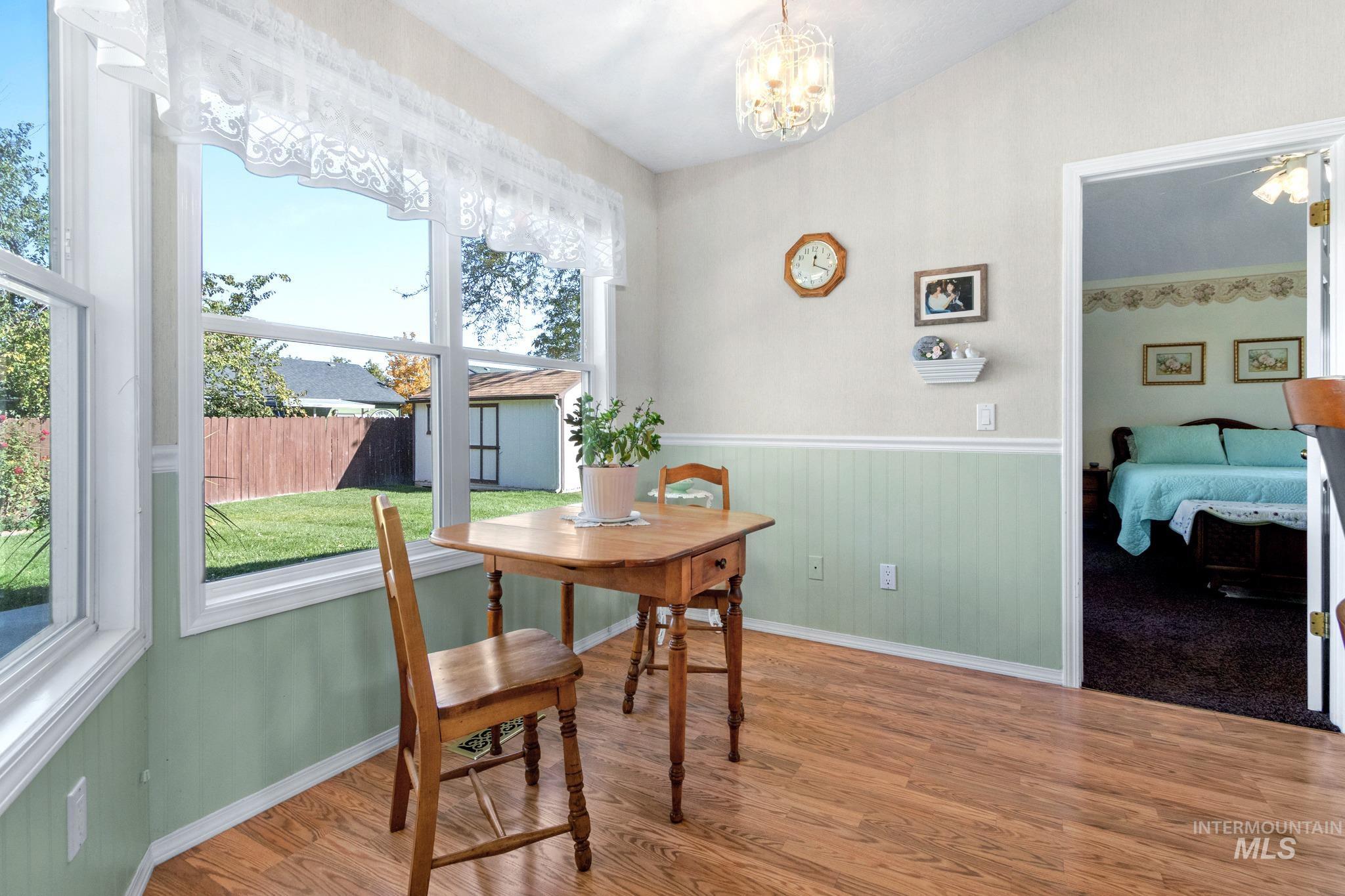 Dining area with wainscoting, wood finished floors, and a chandelier