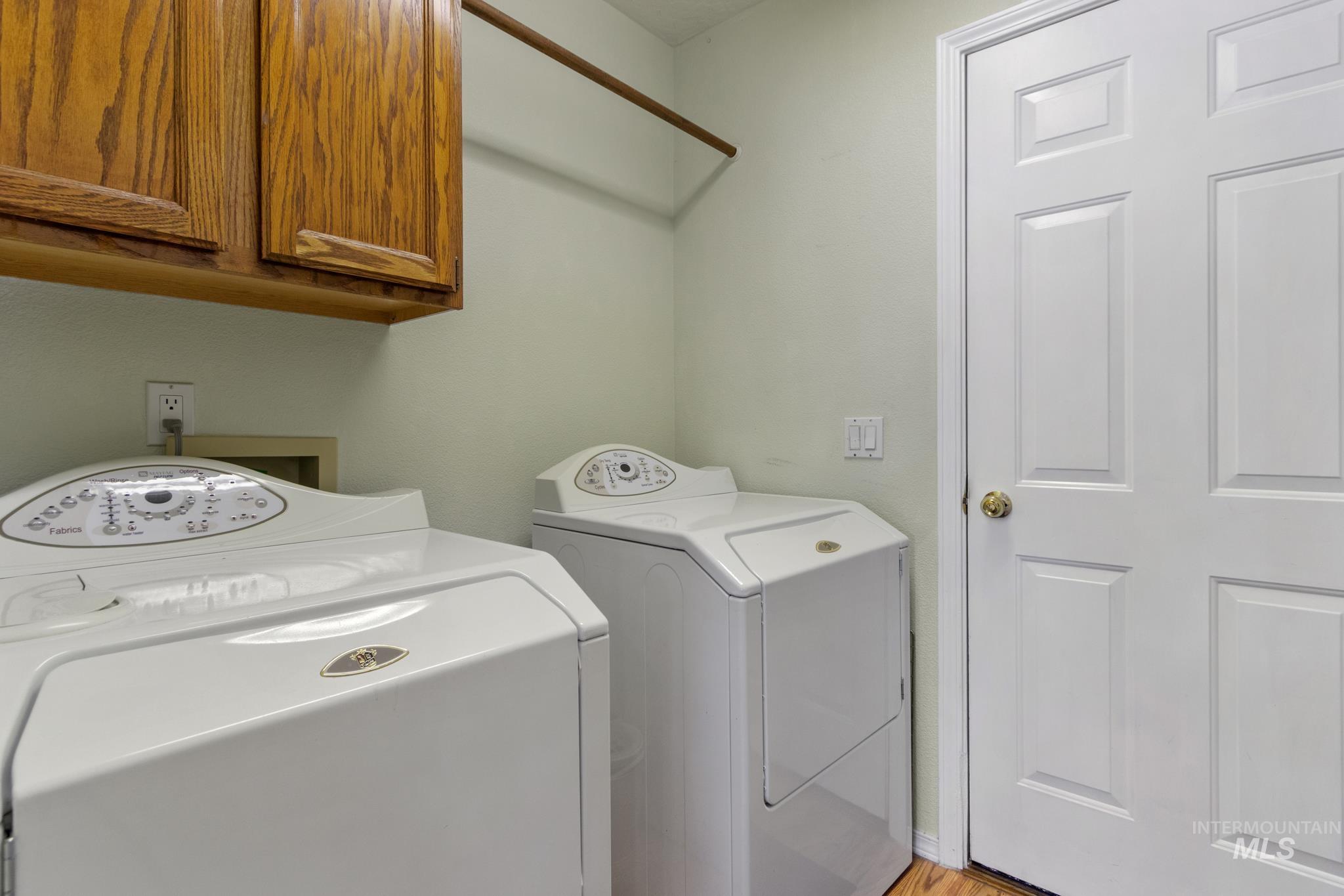 Laundry room featuring washer and clothes dryer, cabinet space, and light wood-type flooring