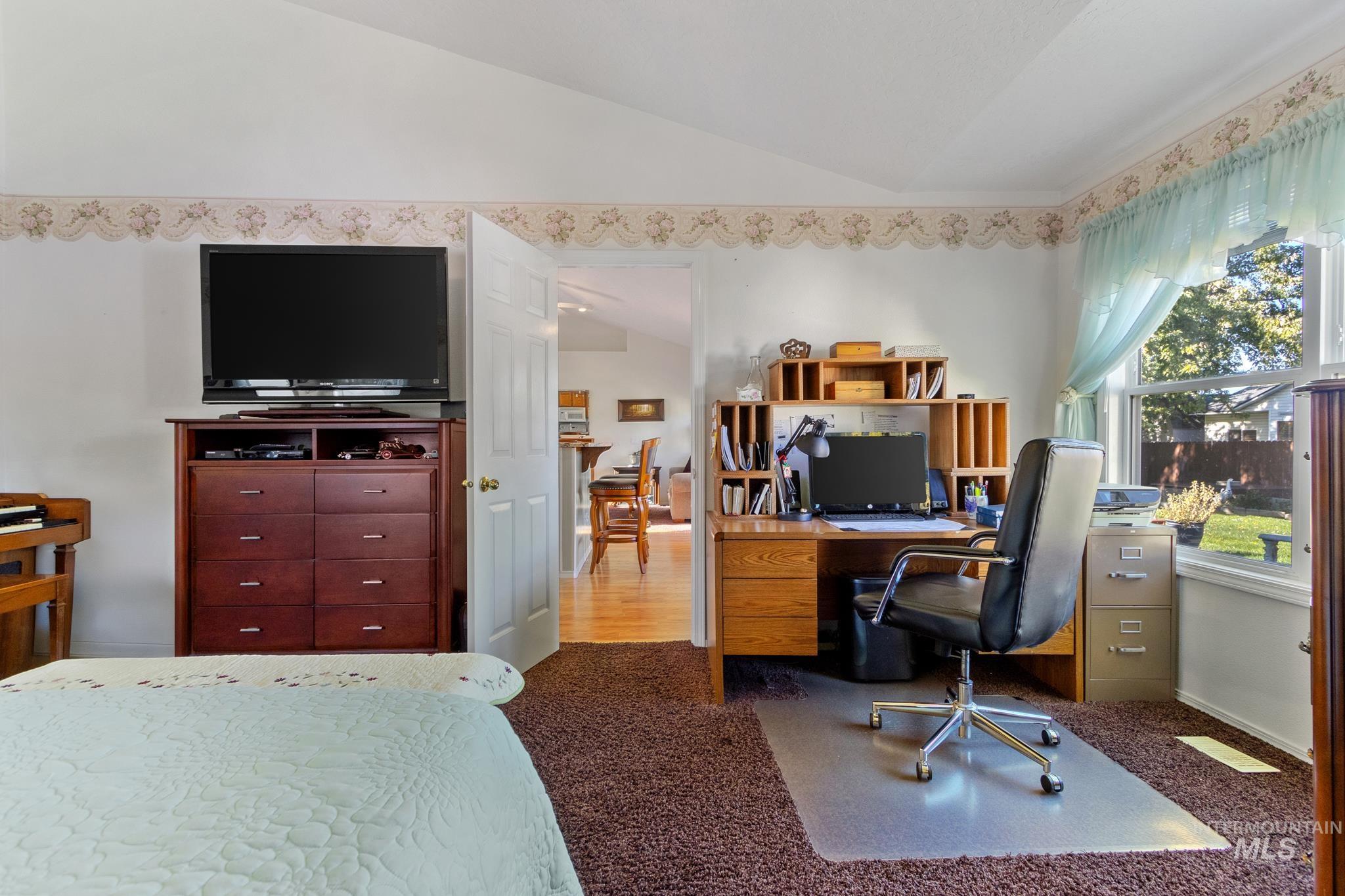 Home office with lofted ceiling and carpet flooring