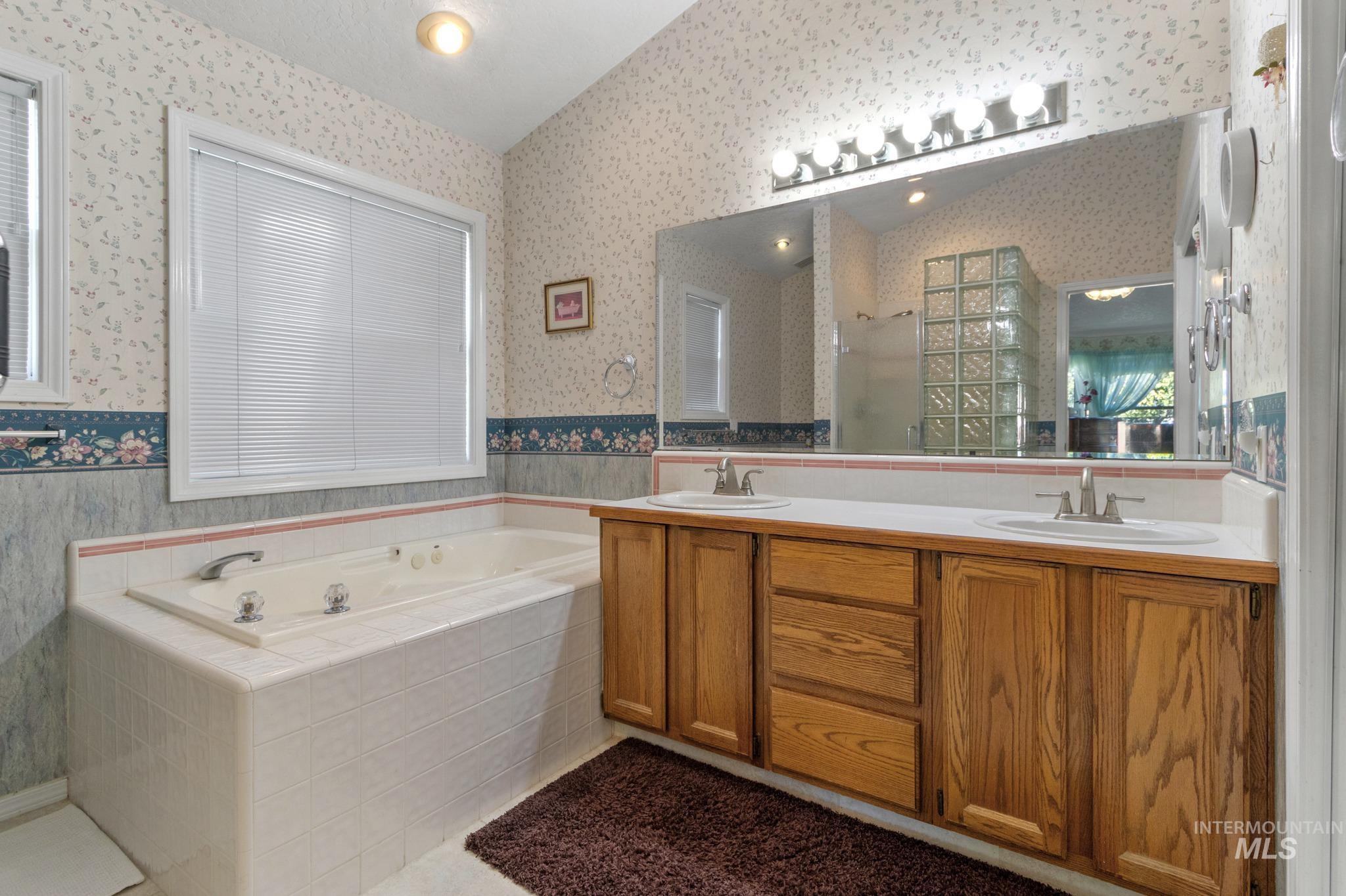 Bathroom with double vanity, a garden tub, a stall shower, wallpapered walls, and light tile patterned floors
