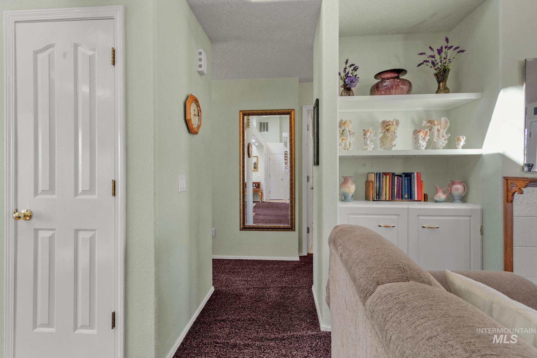 Hallway featuring dark colored carpet and a textured ceiling