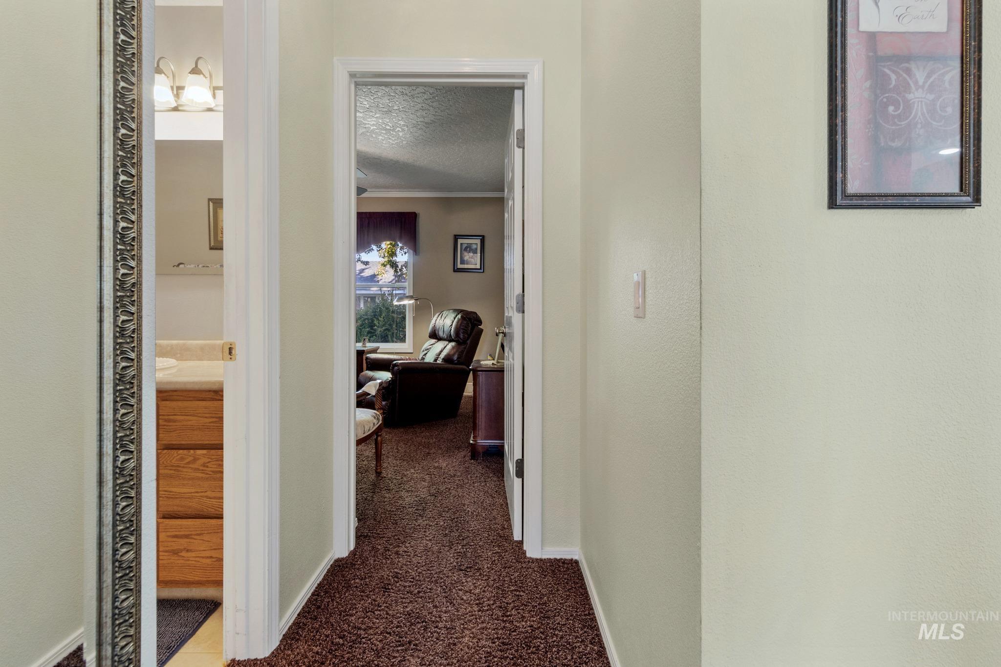 Corridor with dark colored carpet and a textured ceiling