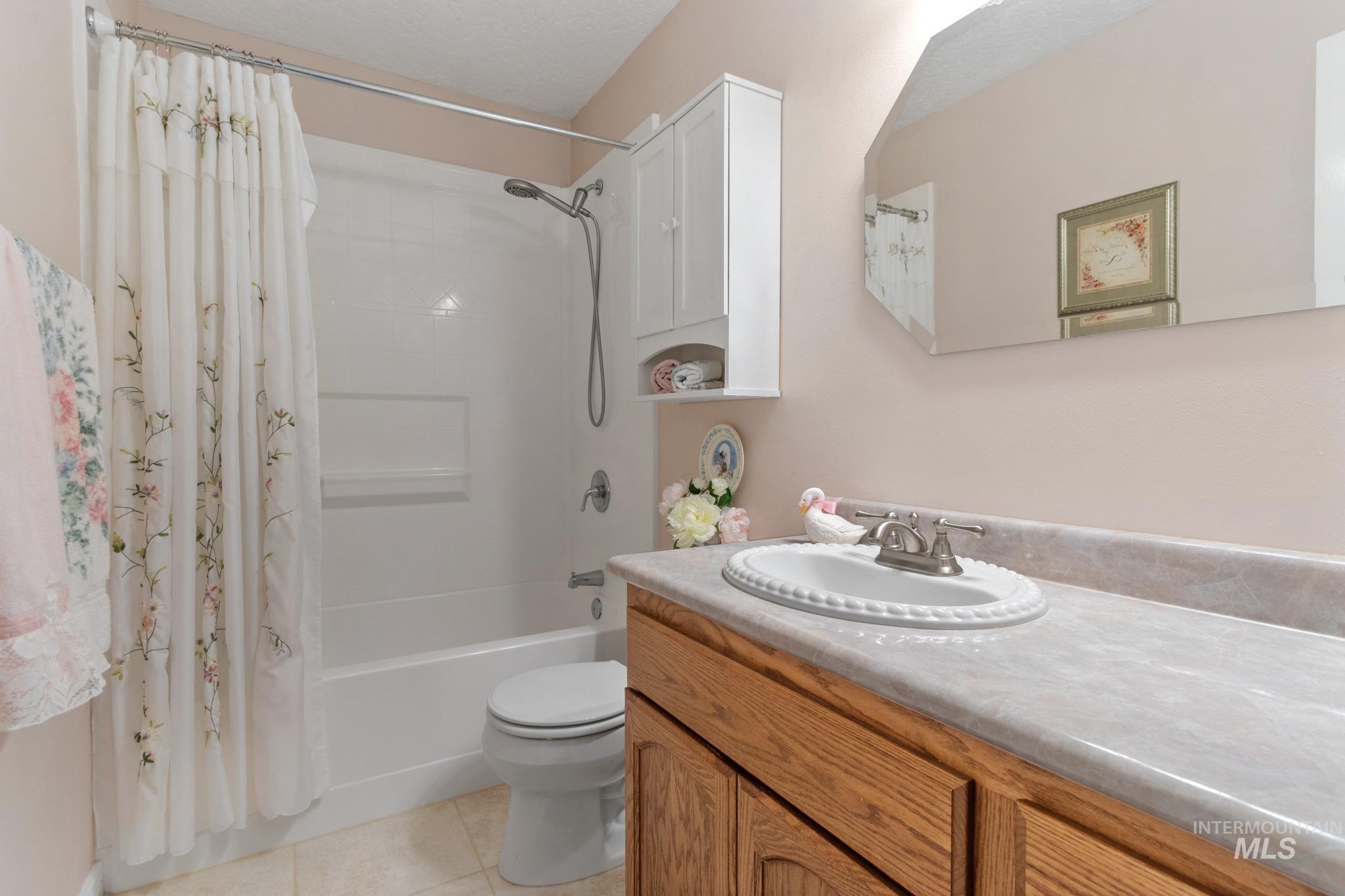 Full bathroom with shower / tub combo with curtain, light tile patterned flooring, and vanity