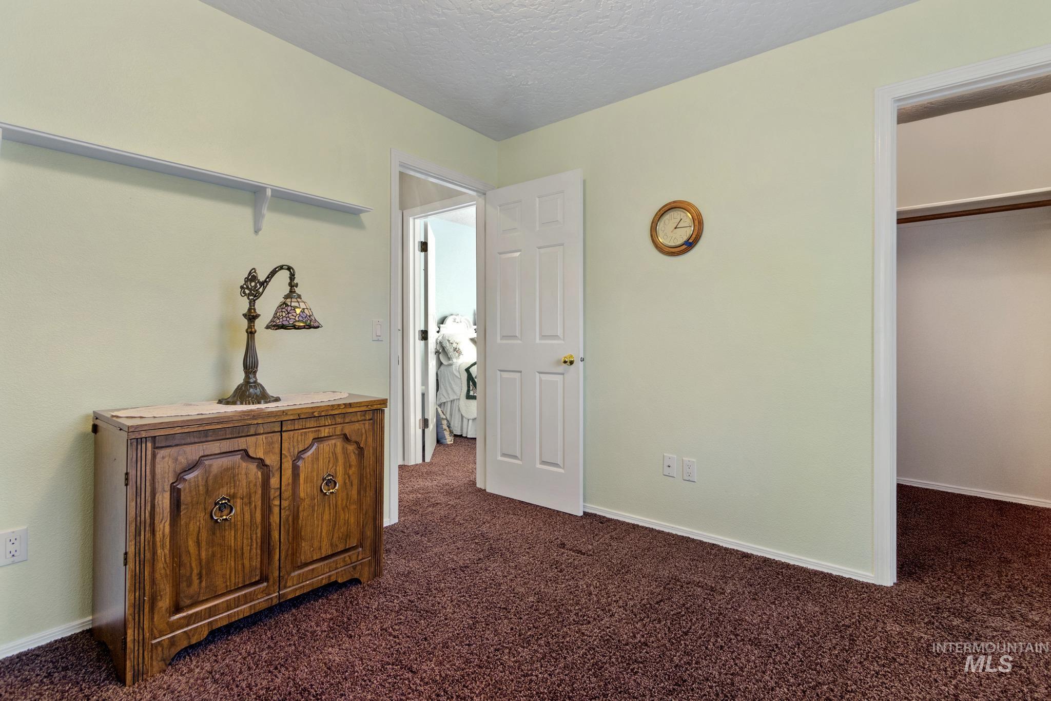 Bedroom featuring dark colored carpet, a walk in closet, and a textured ceiling