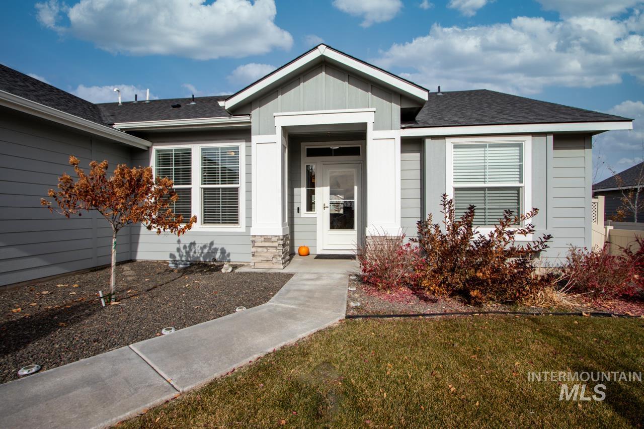 View of exterior entry featuring a shingled roof, a yard, and board and batten siding