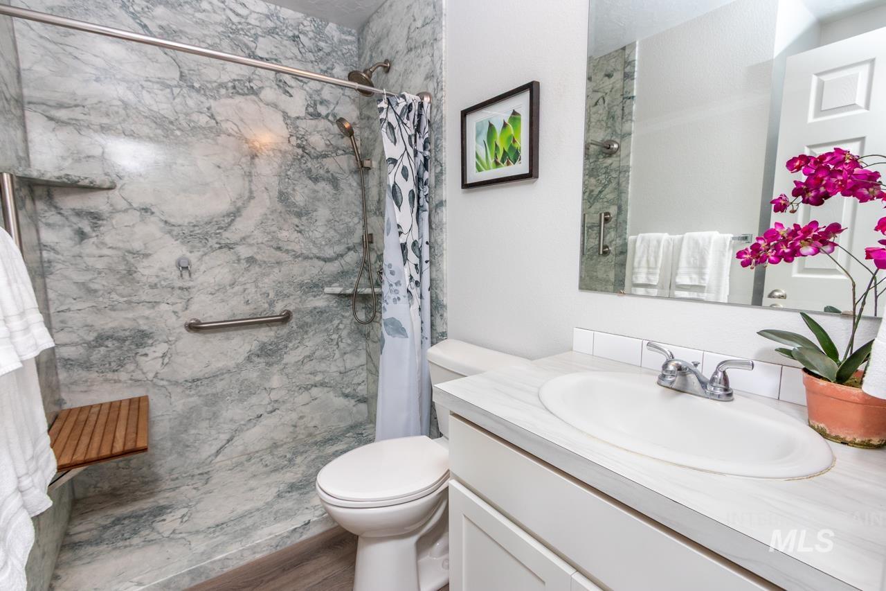 Full bath featuring vanity, a marble finish shower, and wood finished floors