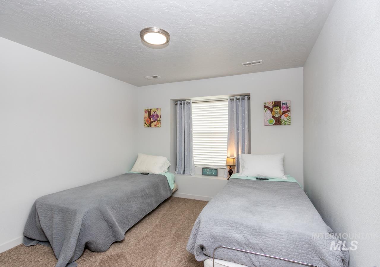 Carpeted bedroom featuring a textured ceiling and baseboards