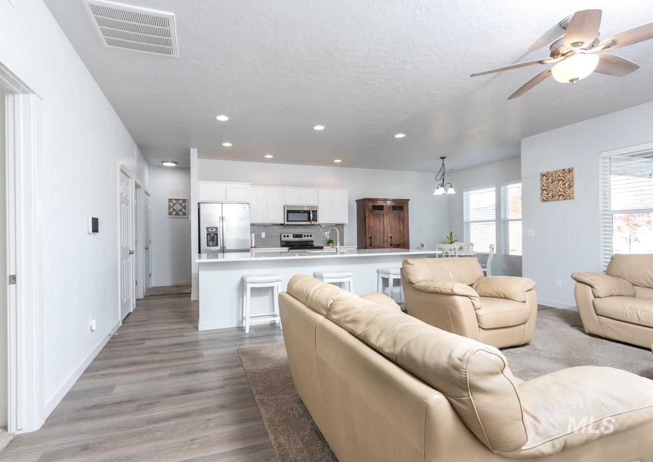 Living room with recessed lighting, light wood-type flooring, a textured ceiling, ceiling fan, and a chandelier
