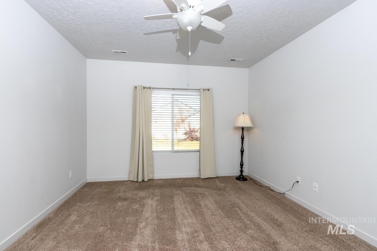 Carpeted spare room with a textured ceiling and ceiling fan