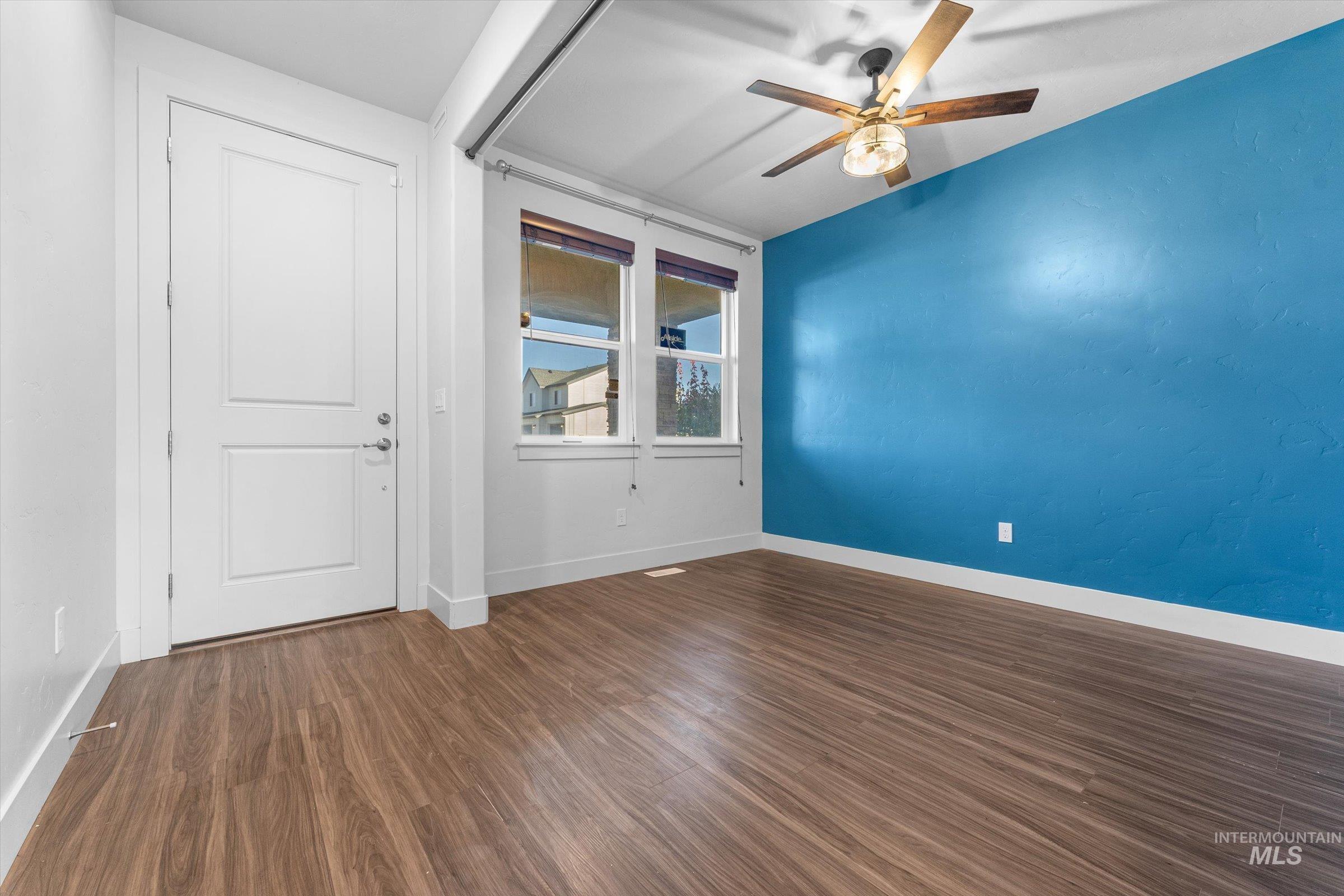 Spare room featuring dark wood-type flooring and a ceiling fan