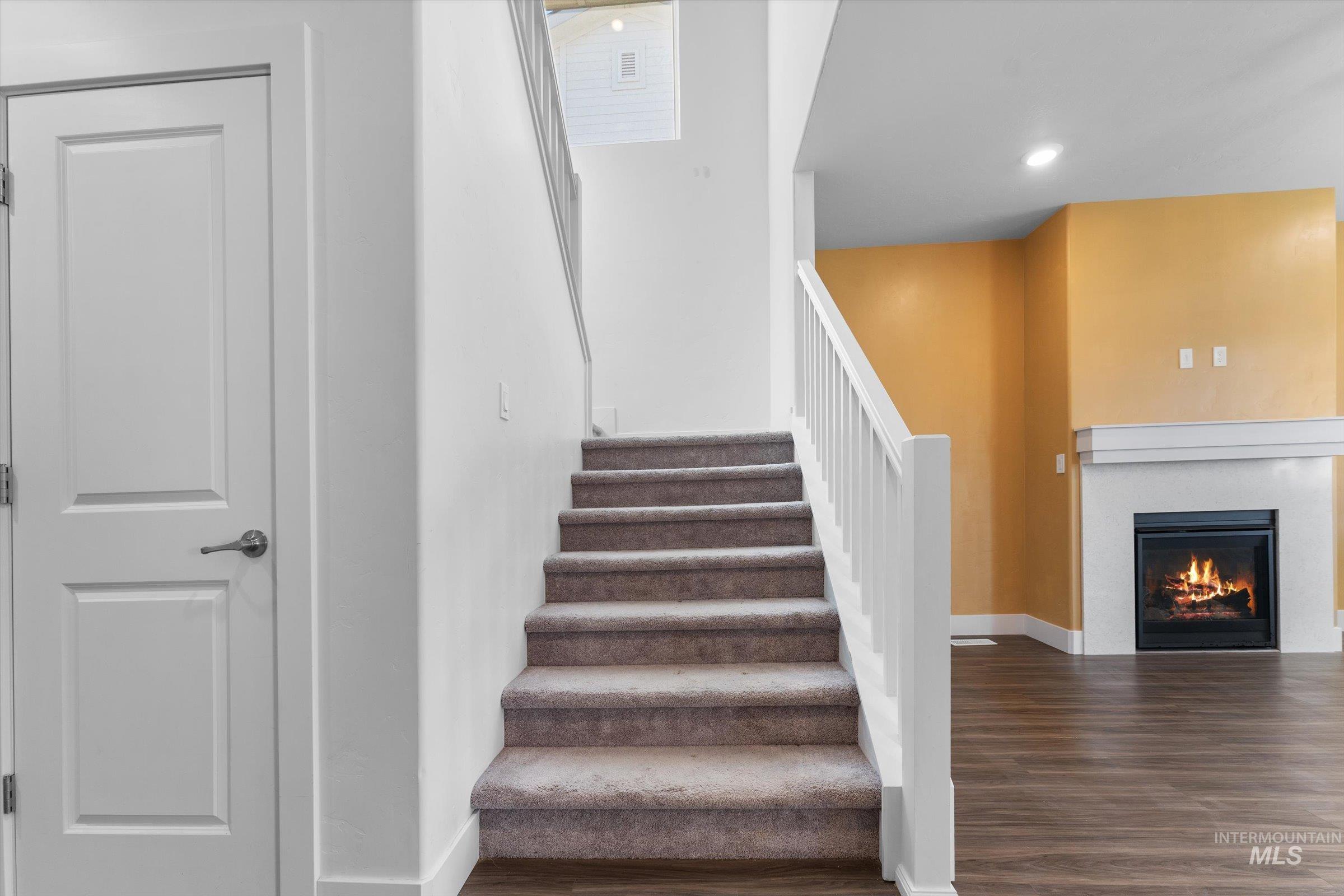 Stairs featuring wood finished floors, a glass covered fireplace, and recessed lighting
