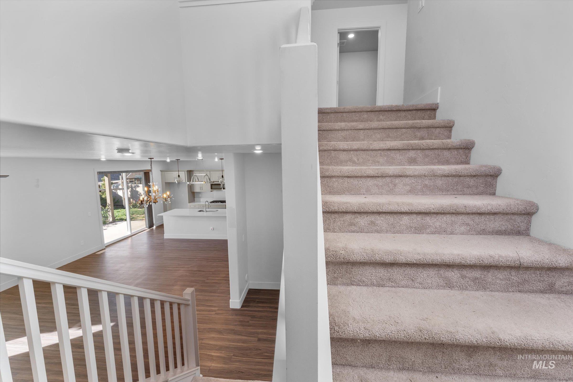 Staircase featuring wood finished floors, a chandelier, and a high ceiling