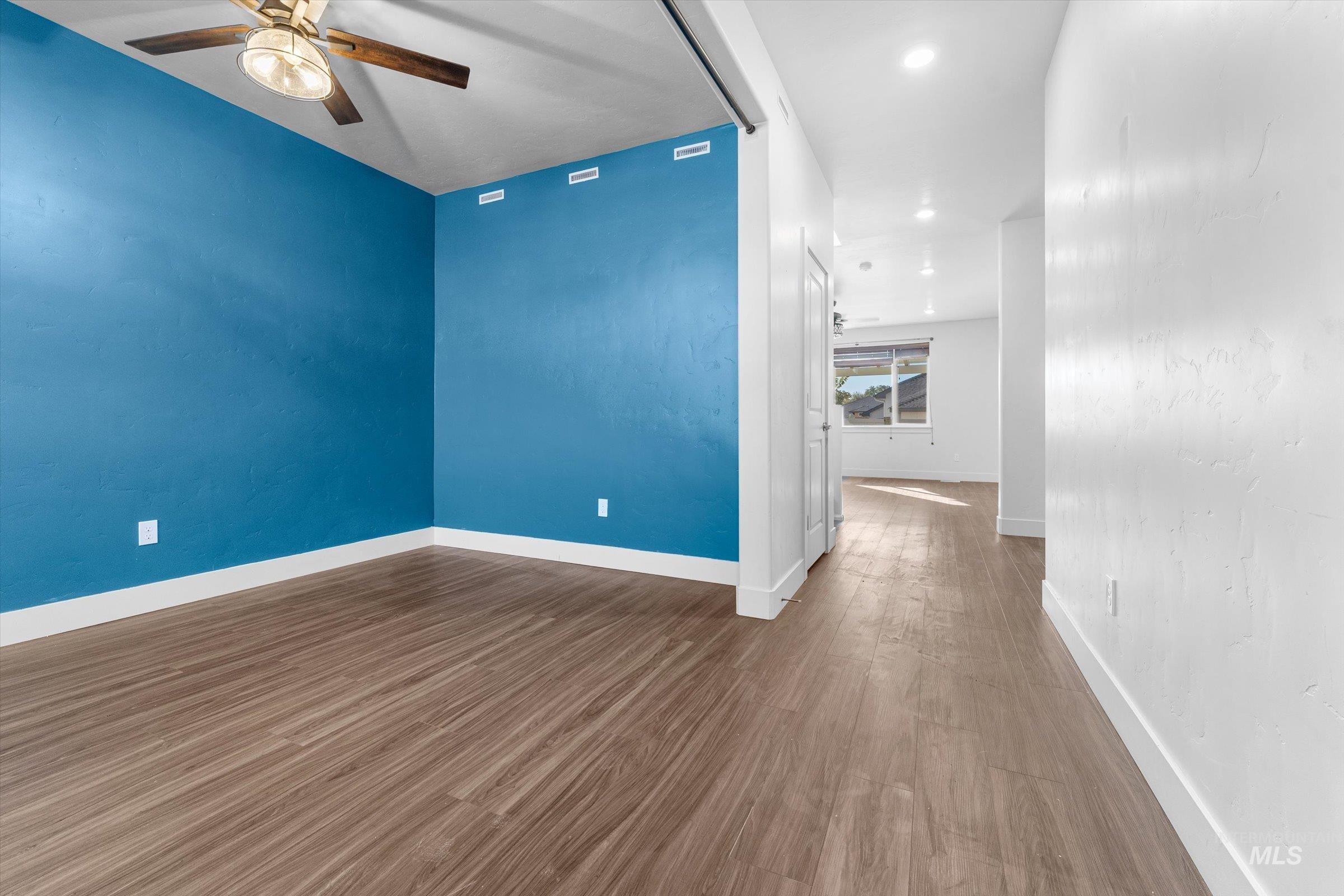 Empty room featuring dark wood-style floors, a ceiling fan, and recessed lighting