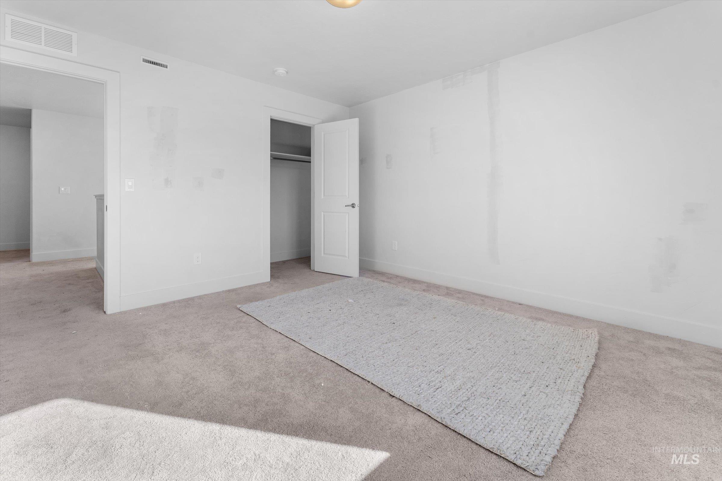 Unfurnished bedroom with light colored carpet and a closet