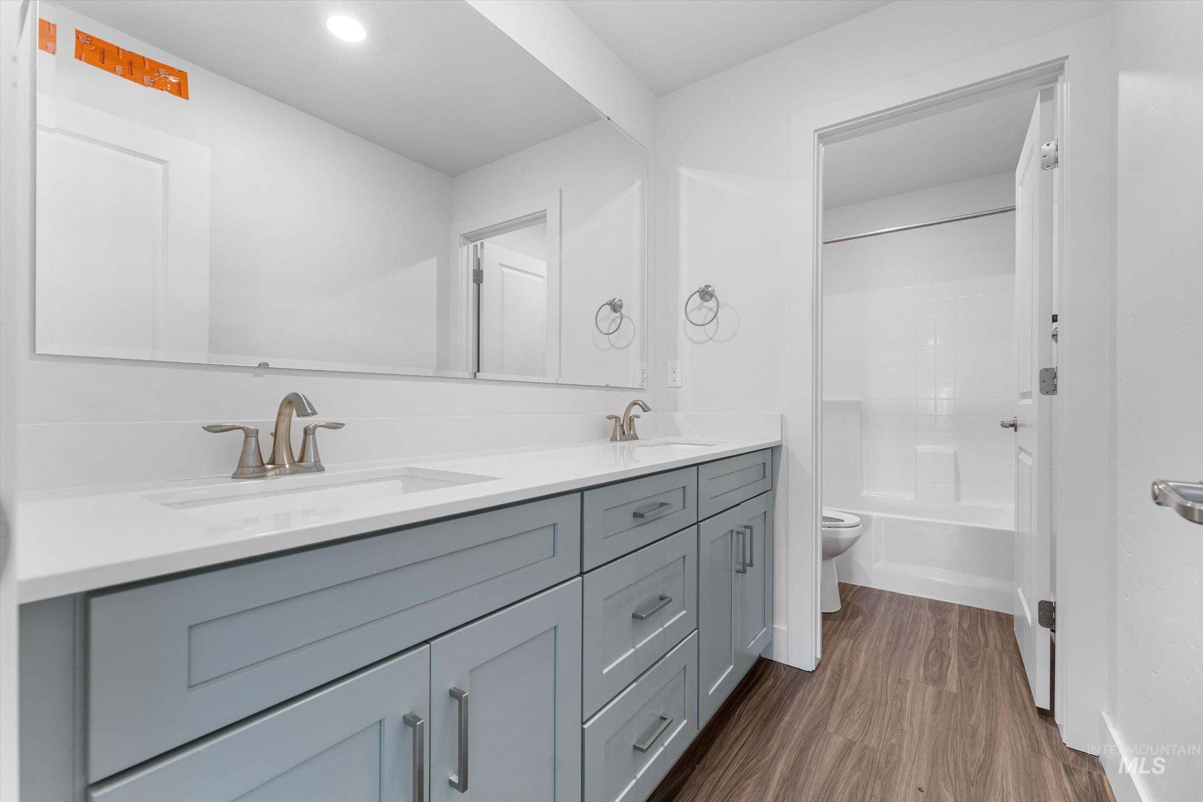 Full bath with double vanity, dark wood-style floors, bathtub / shower combination, and recessed lighting