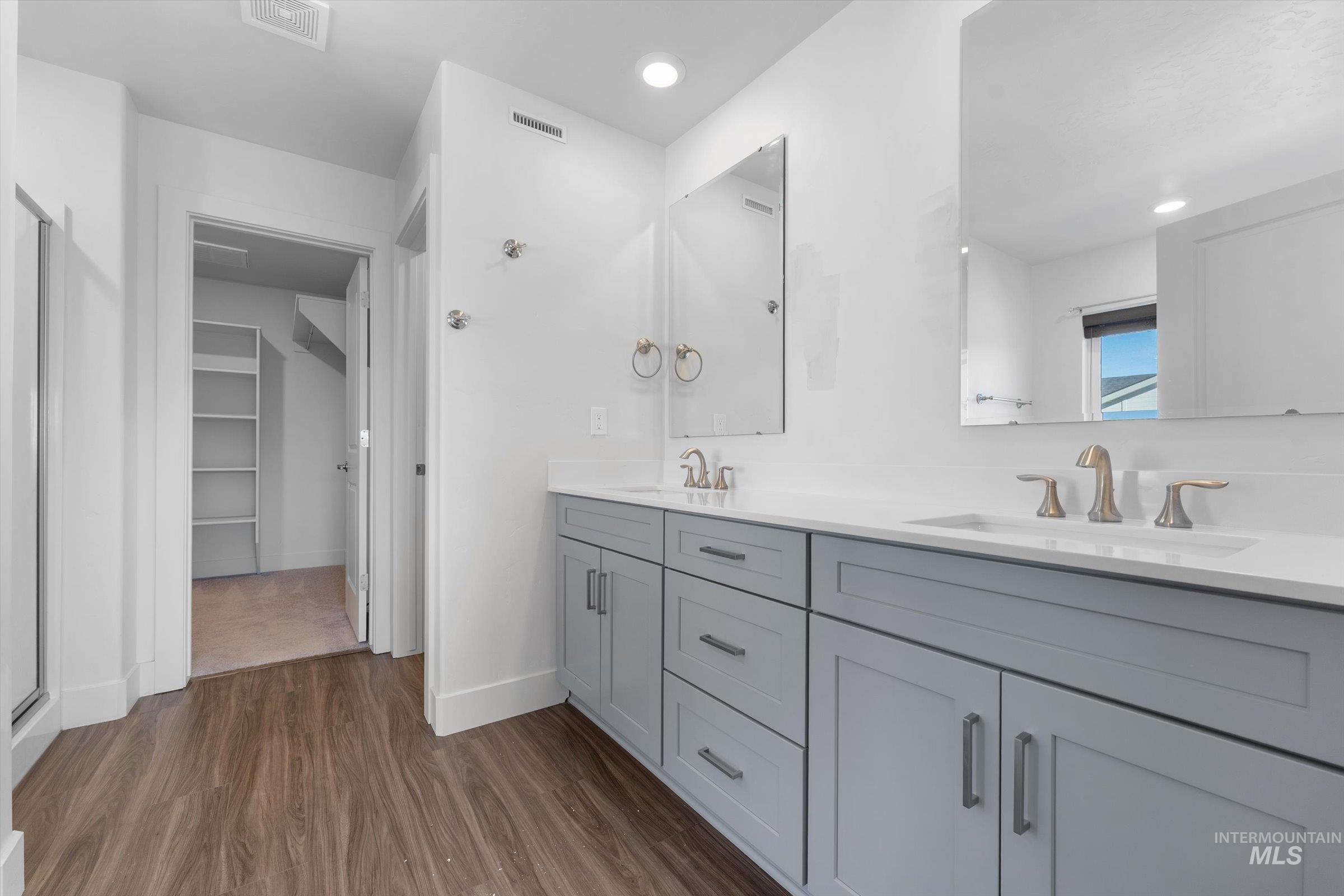 Full bathroom featuring dark wood-style flooring, double vanity, a walk in closet, and recessed lighting