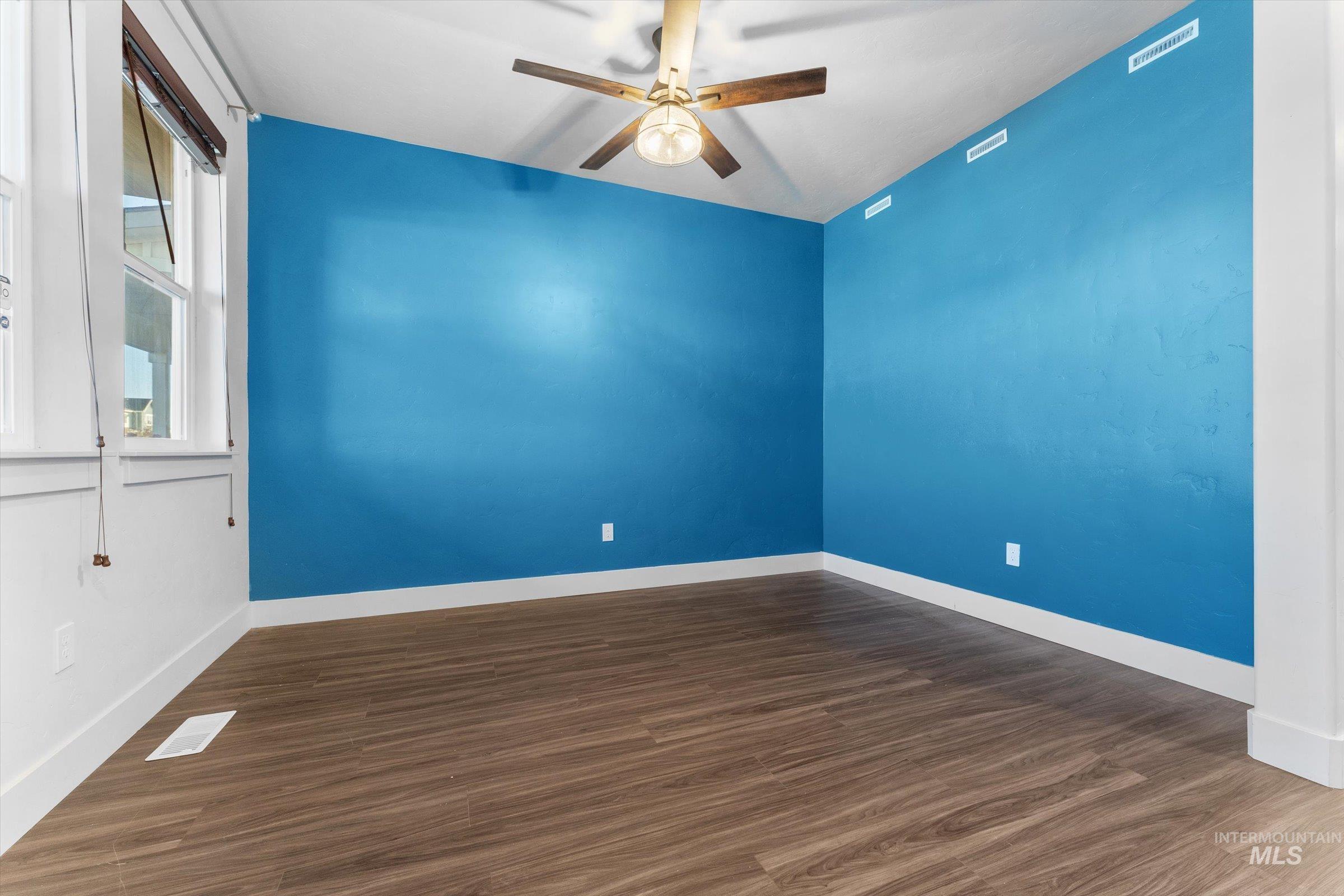 Unfurnished room featuring dark wood finished floors and a ceiling fan