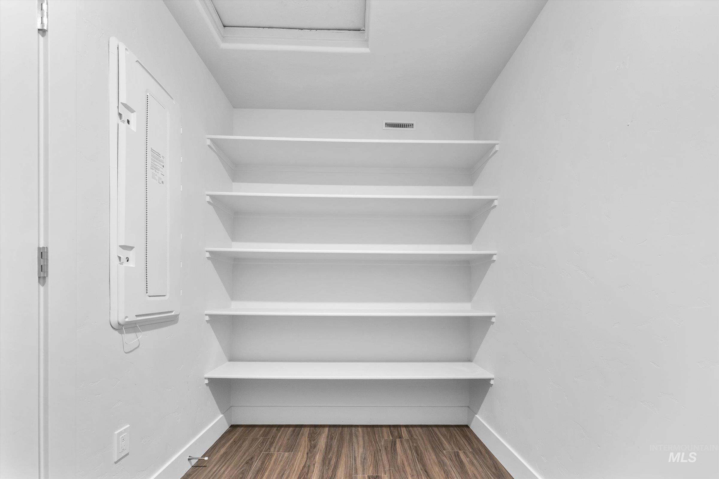 Spacious closet featuring dark wood-style floors and electric panel