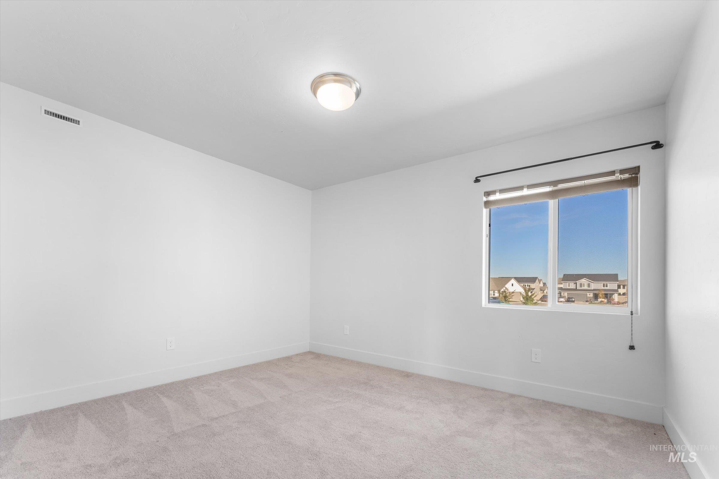 Spare room featuring light carpet and baseboards