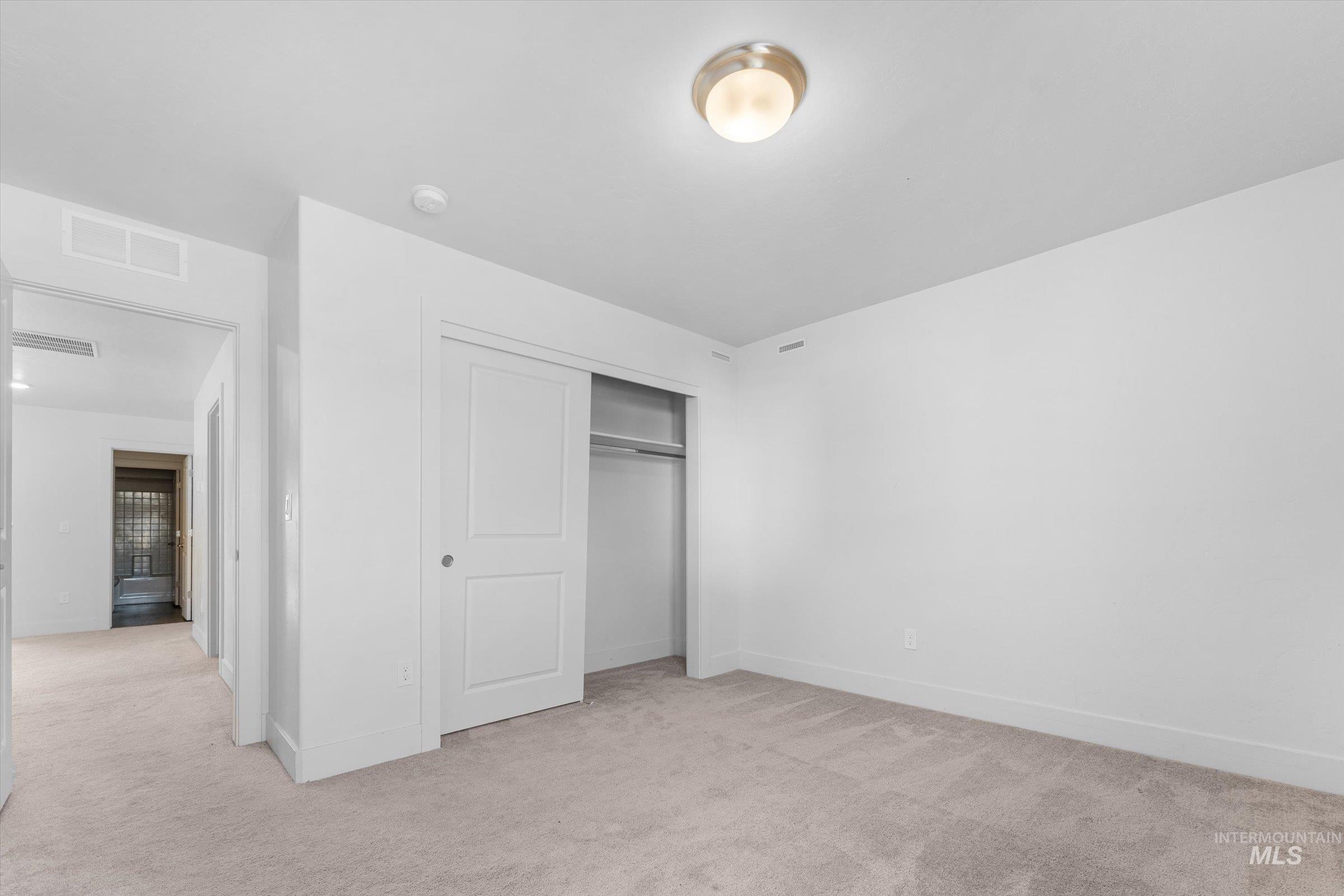 Unfurnished bedroom featuring light carpet and a closet