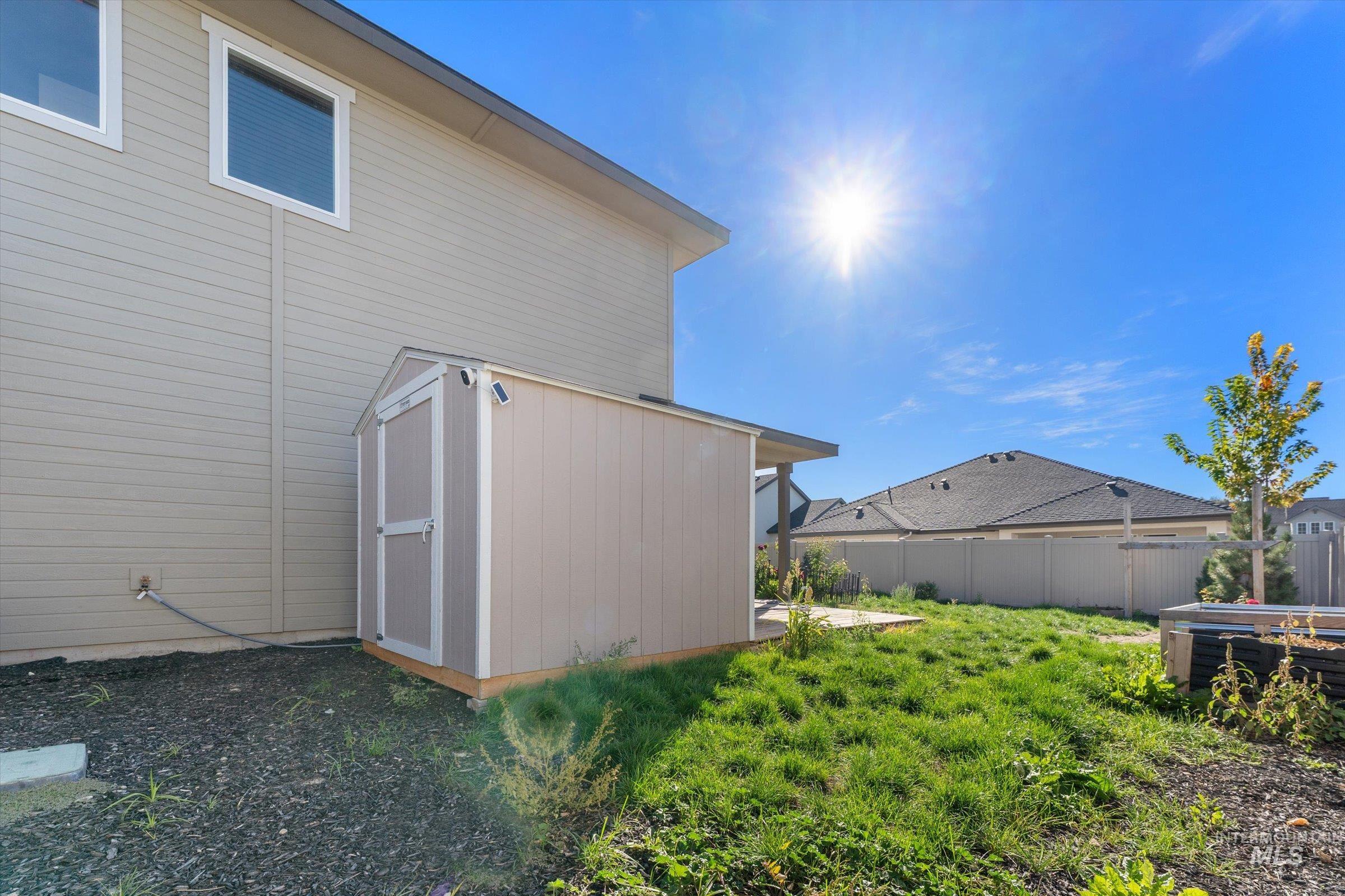View of side of property featuring a storage unit, a fenced backyard, and a patio