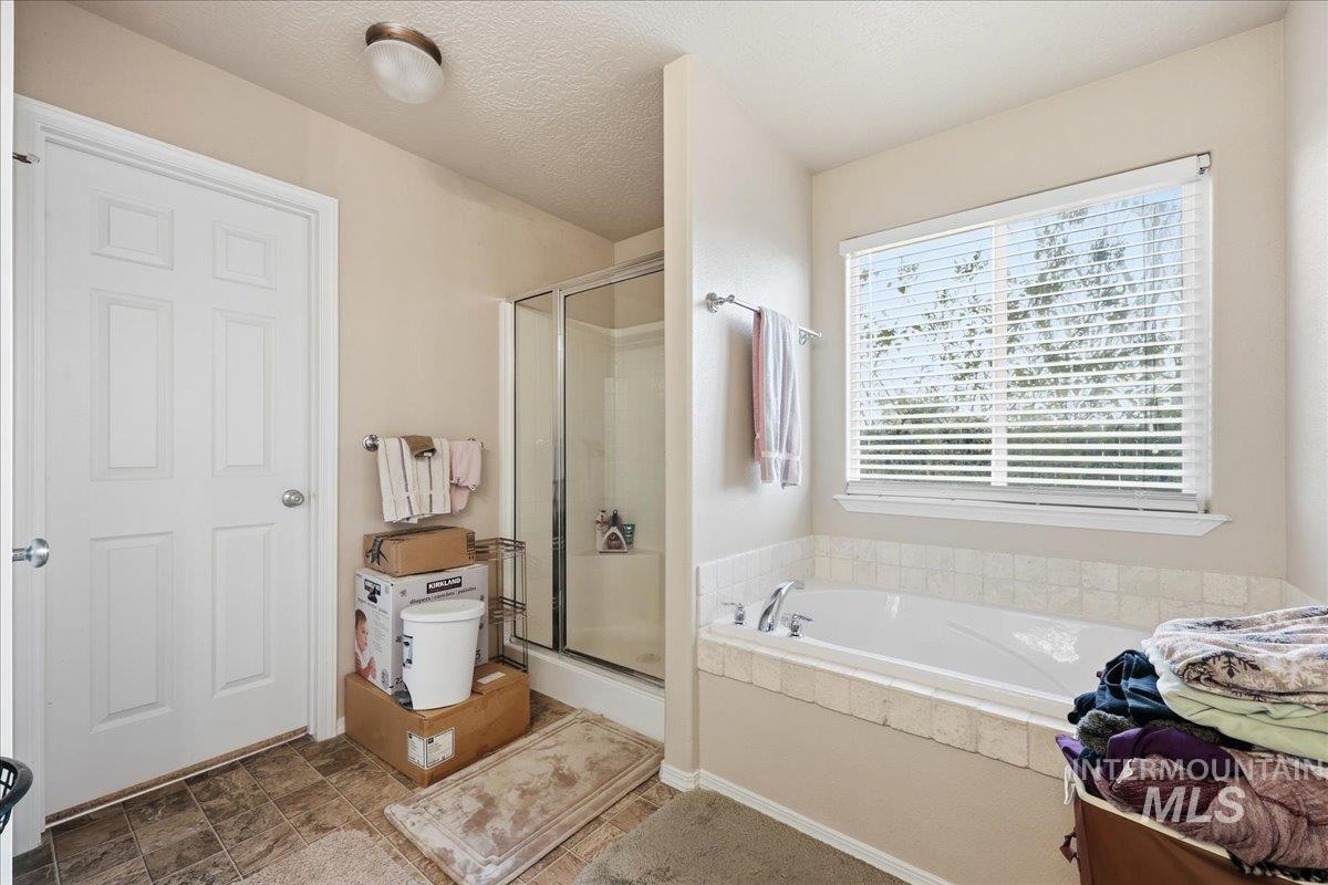 Bathroom featuring a shower stall, a garden tub, and a textured ceiling