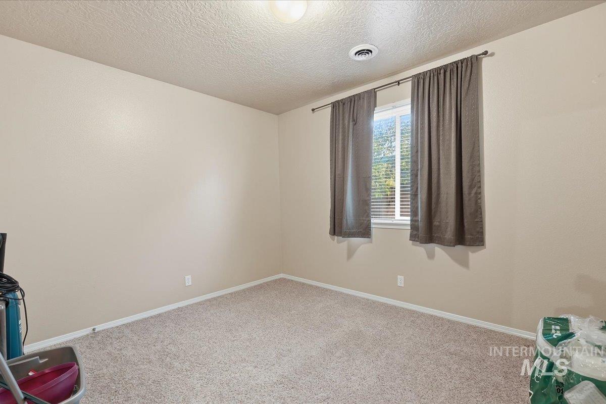 Unfurnished room featuring carpet and a textured ceiling