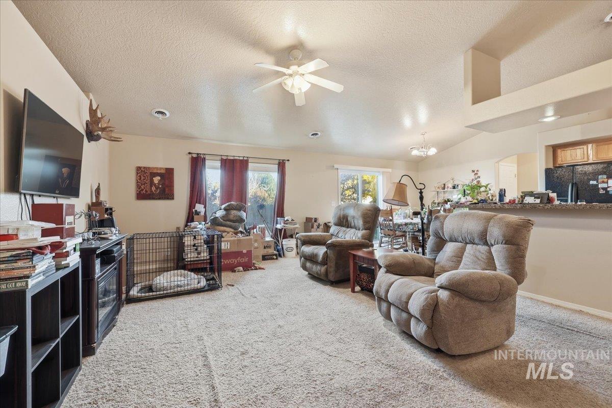 Living area featuring light carpet, a textured ceiling, ceiling fan, and a chandelier