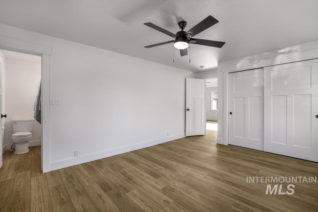 Unfurnished bedroom with wood finished floors, a closet, and a ceiling fan