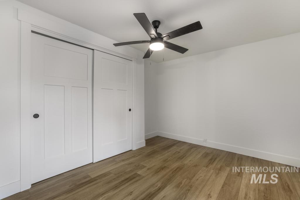 Unfurnished bedroom featuring wood finished floors, a closet, and a ceiling fan