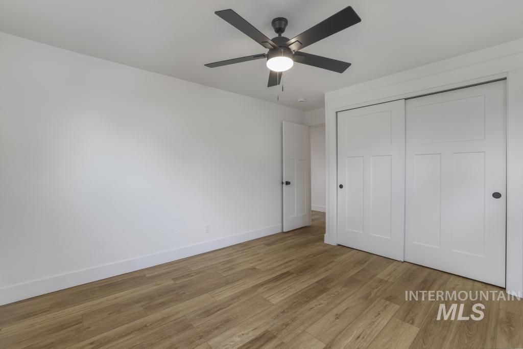 Unfurnished bedroom with wood finished floors, ceiling fan, and a closet