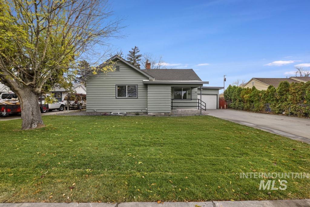 View of front of house with a front lawn, a chimney, driveway, and a garage