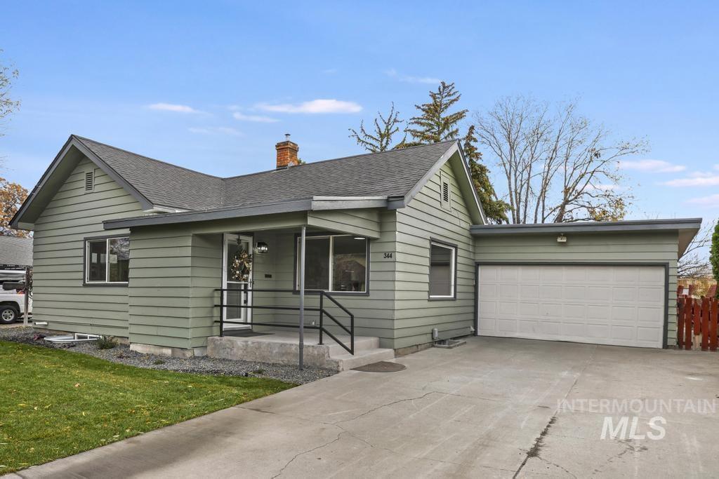 Single story home with a porch, driveway, and roof with shingles