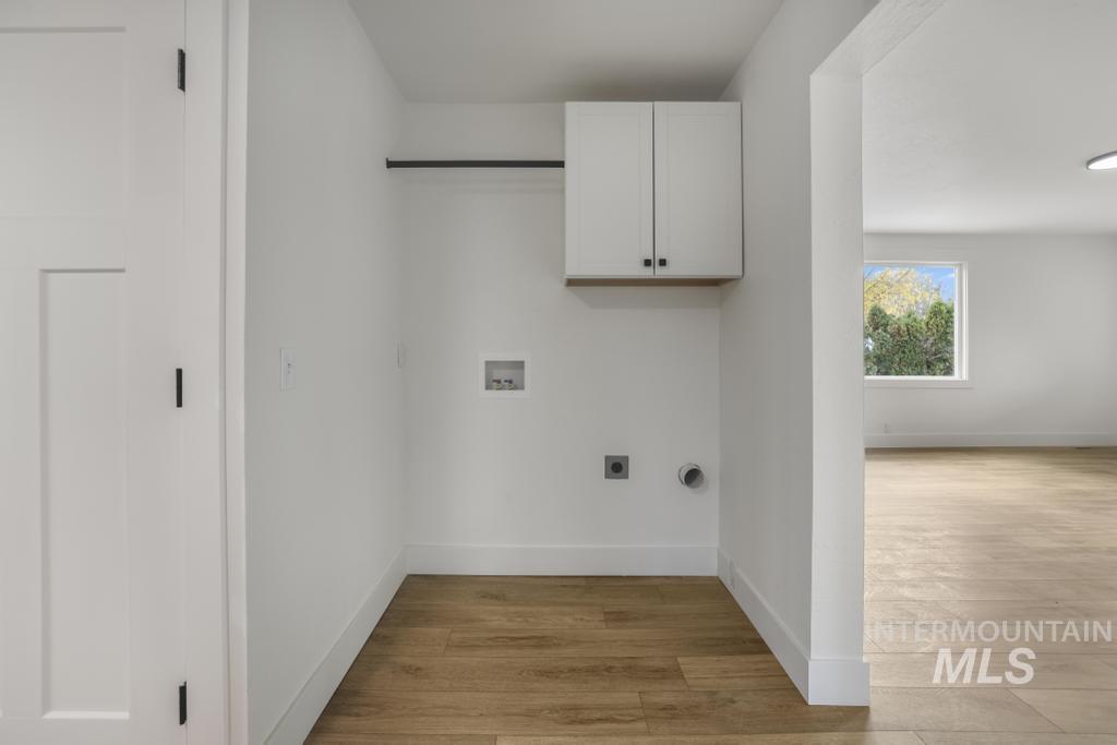 Laundry room with light wood-style flooring, cabinet space, washer hookup, and electric dryer hookup