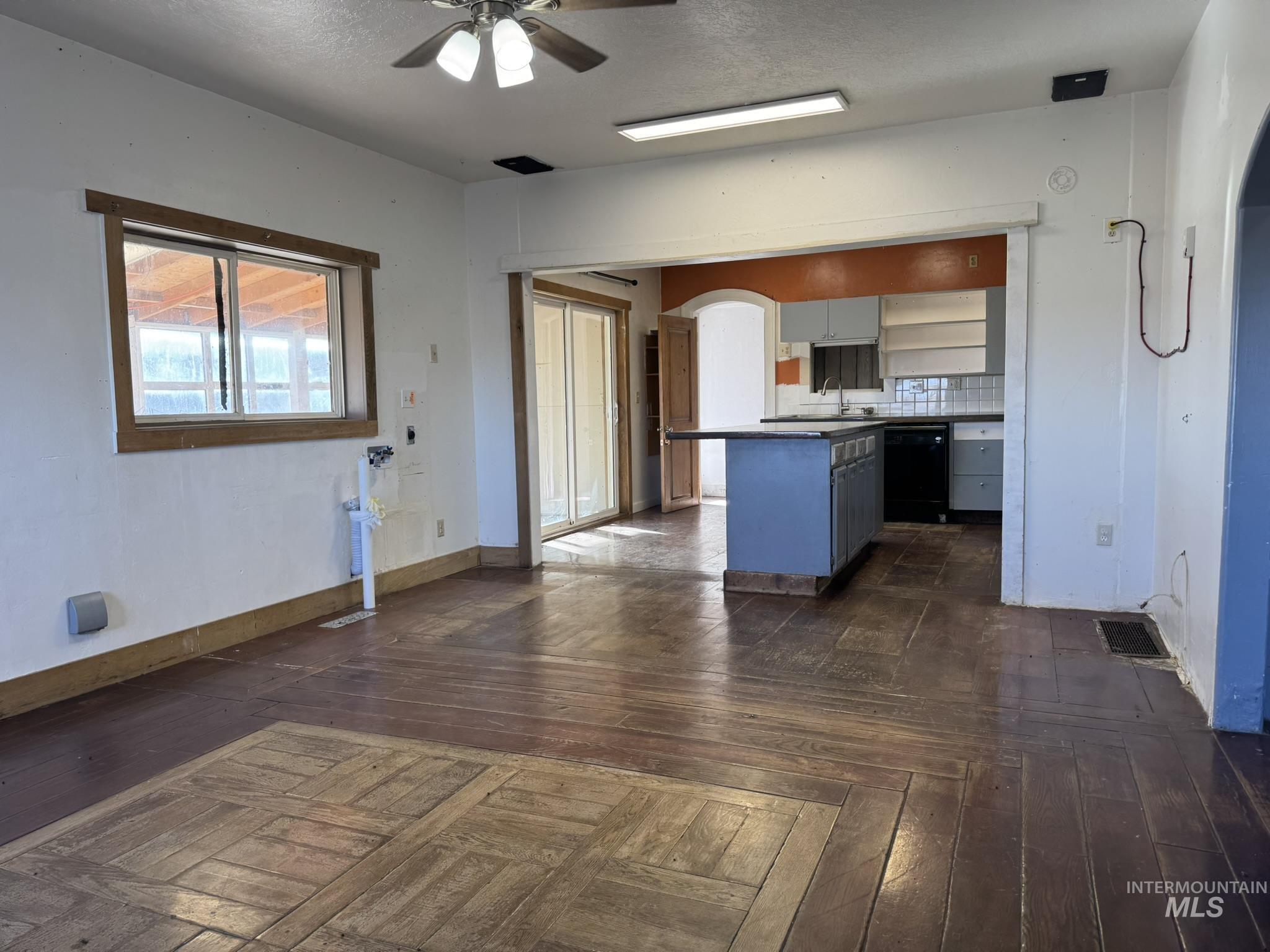 Kitchen with arched walkways, open shelves, a ceiling fan, black dishwasher, and parquet floors