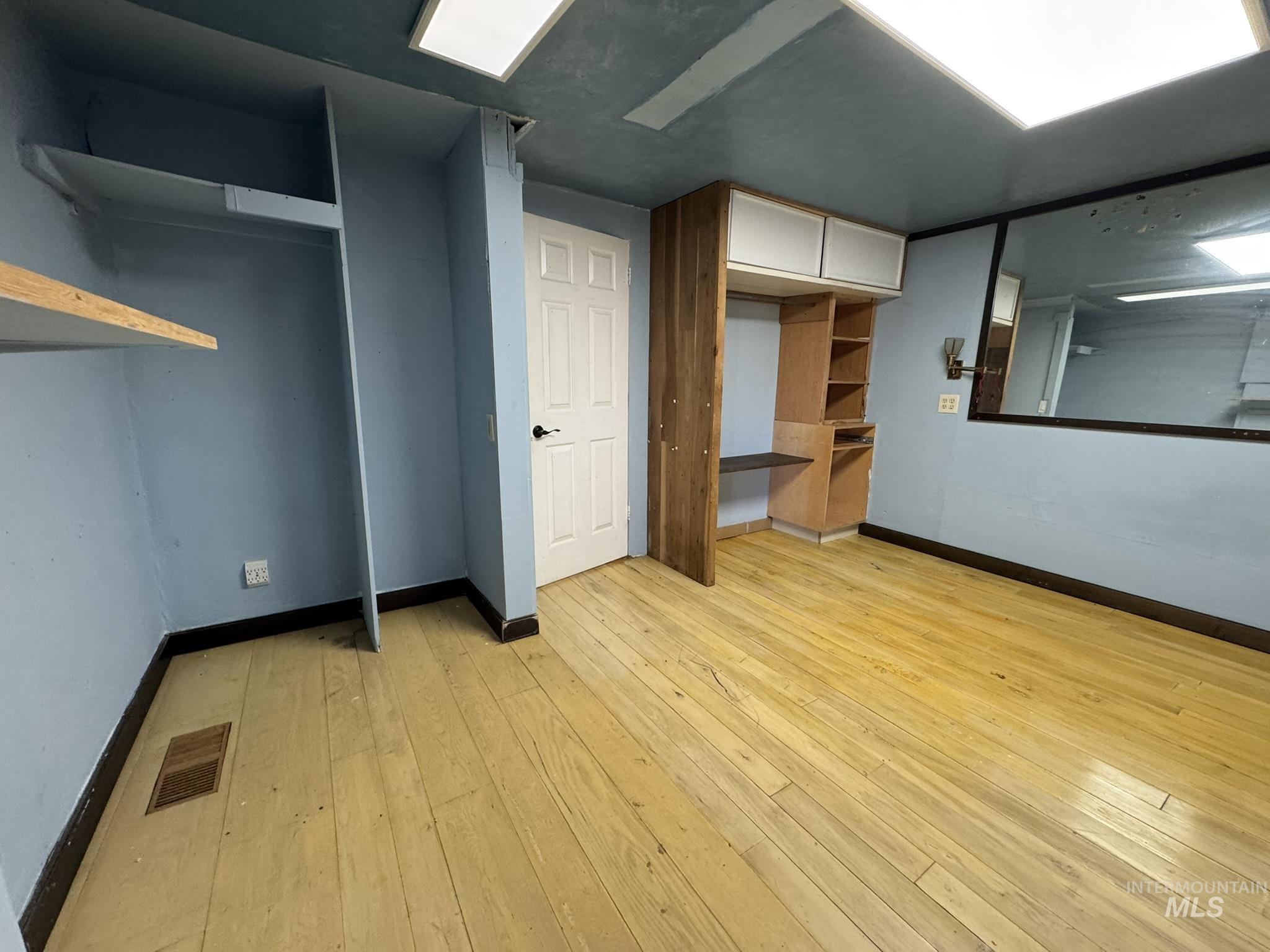 Unfurnished bedroom with baseboards and light wood-type flooring