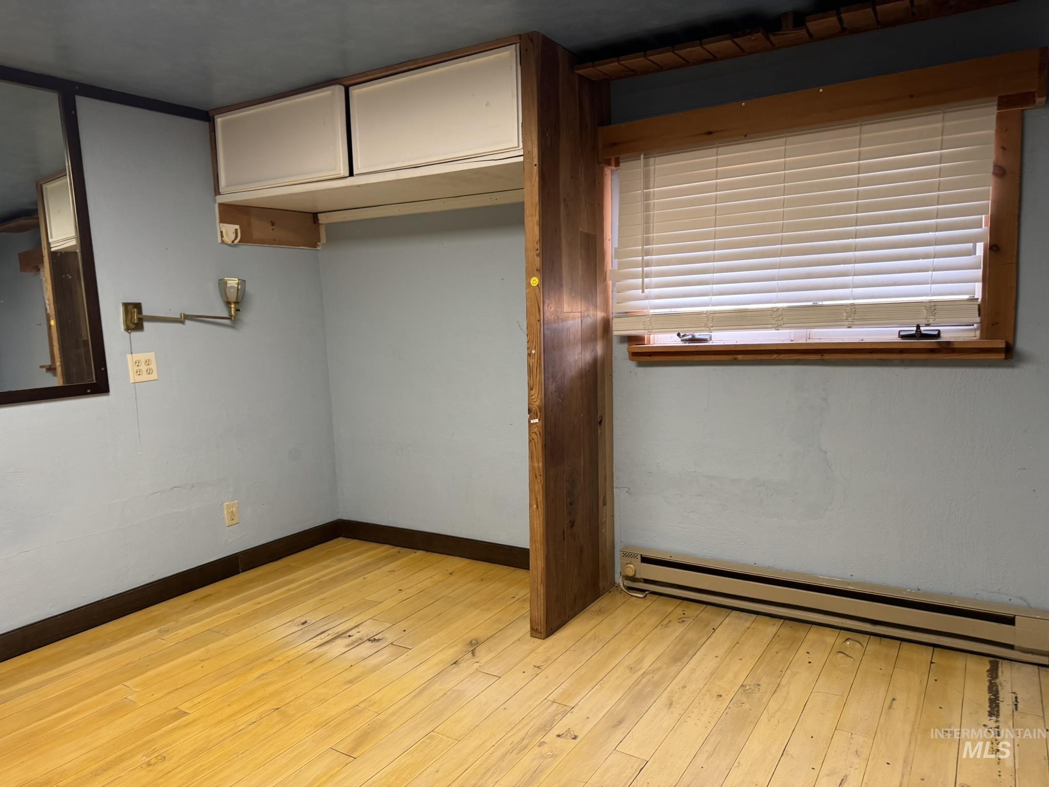 Empty room with a baseboard radiator and light wood-style flooring