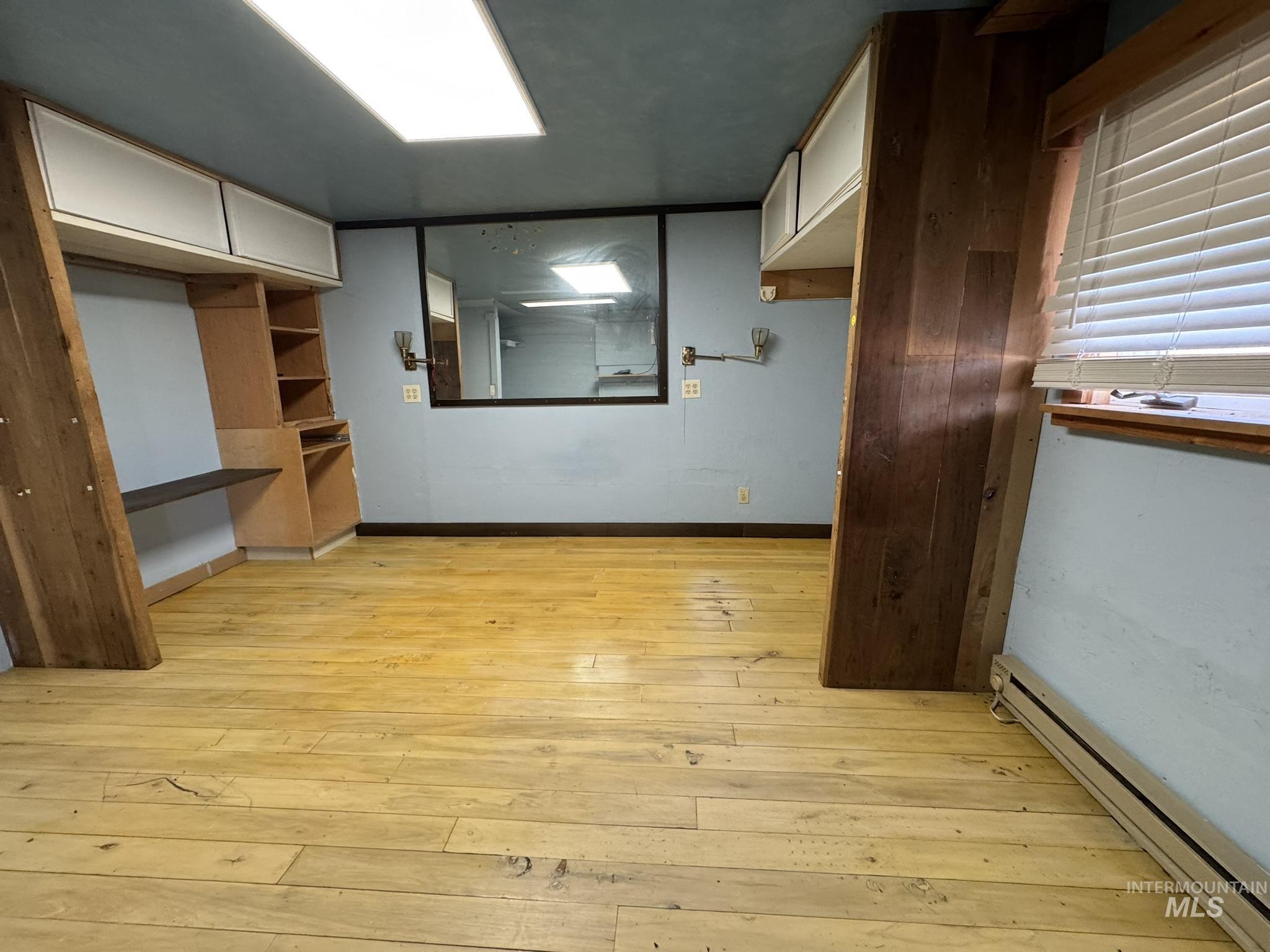 Unfurnished bedroom featuring baseboard heating and light wood-type flooring