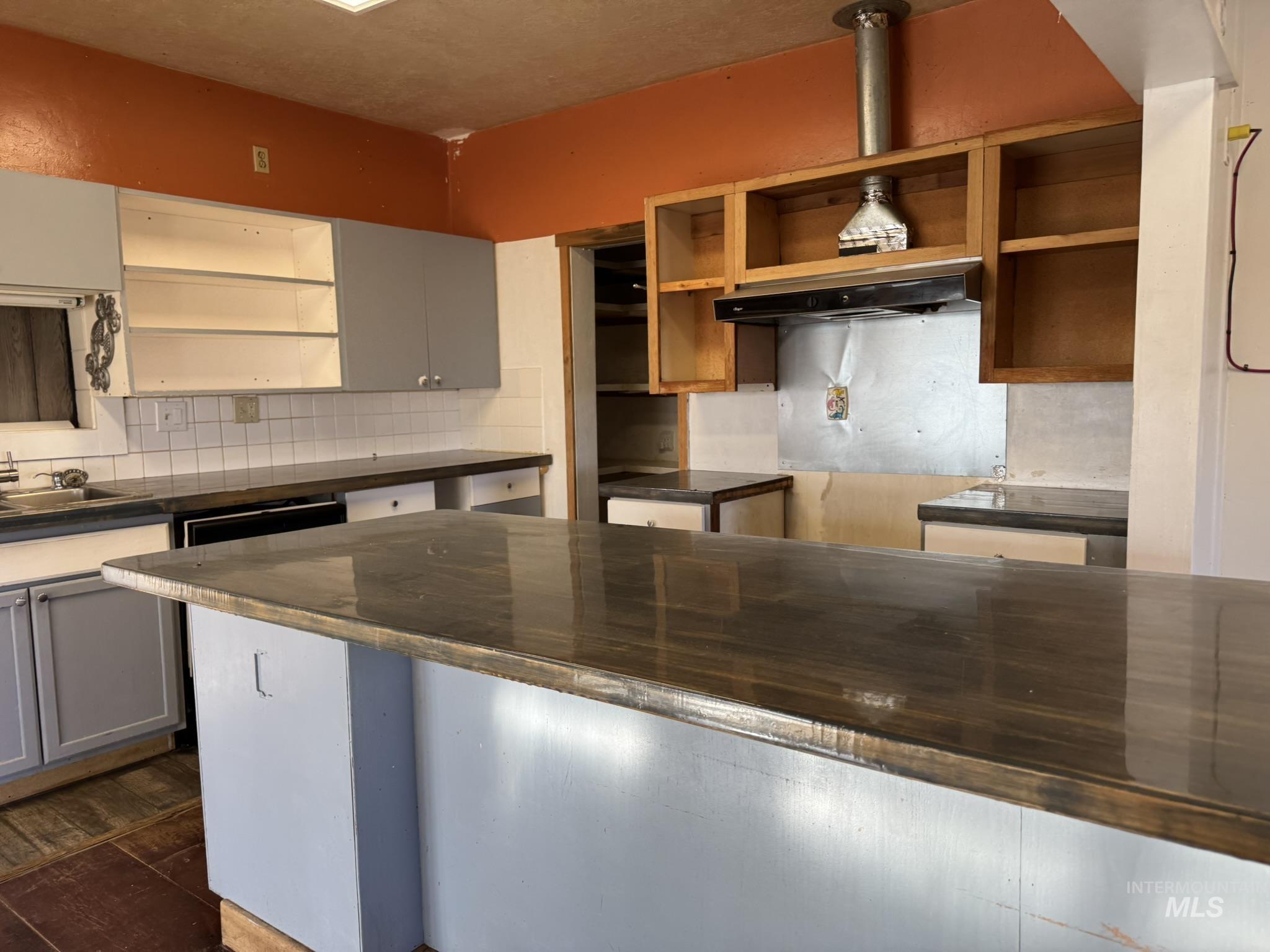 Kitchen featuring dark countertops, open shelves, backsplash, and gray cabinets