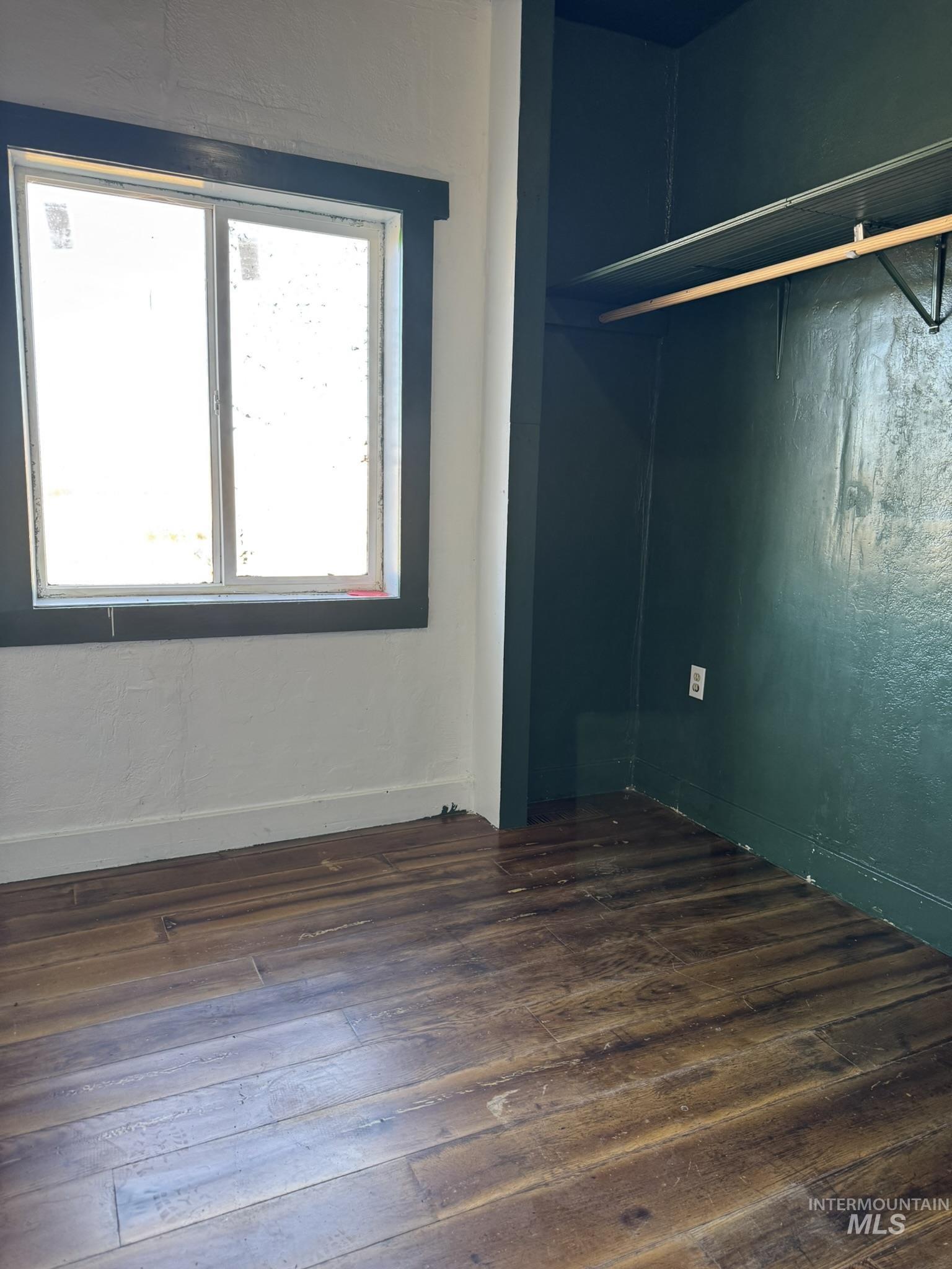 Unfurnished bedroom featuring dark wood-type flooring