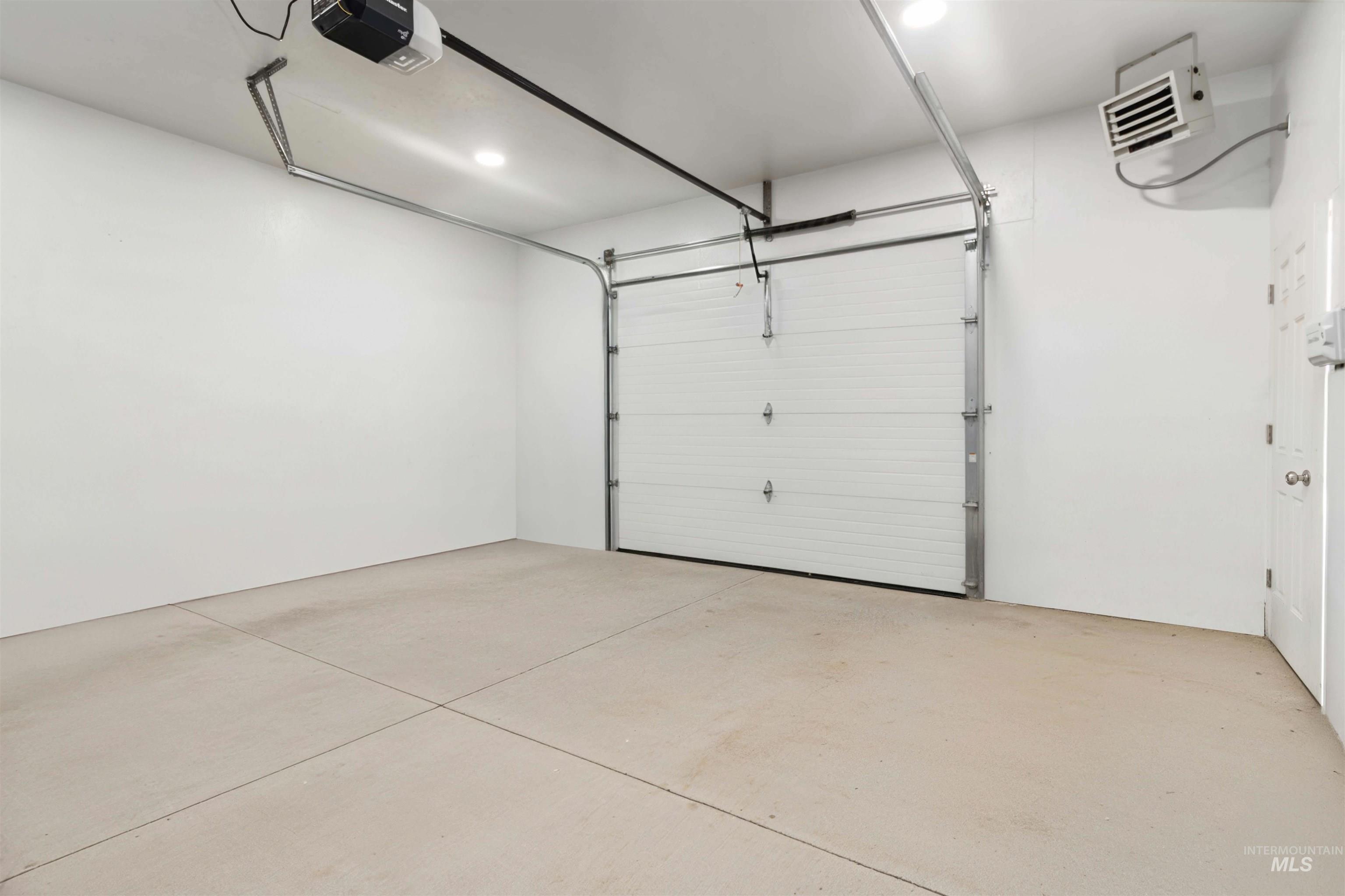 Garage featuring a garage door opener, a heating unit, and recessed lighting