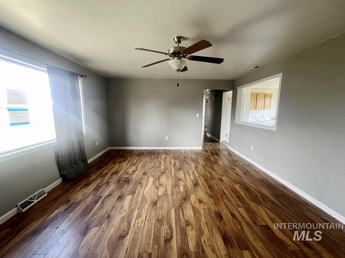 Spare room with dark wood-type flooring and a ceiling fan