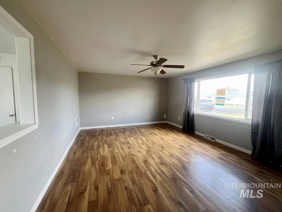 Empty room with wood finished floors and a ceiling fan