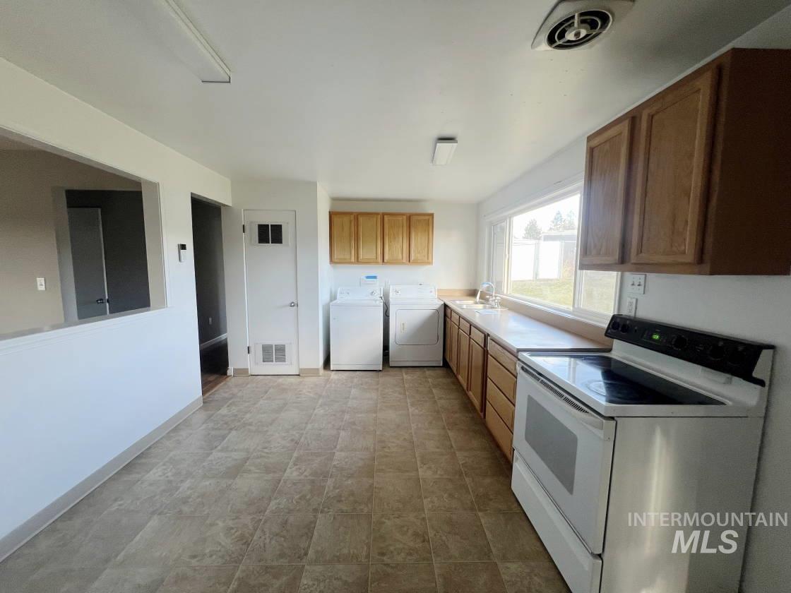 Kitchen with white range with electric stovetop, light countertops, and brown cabinets