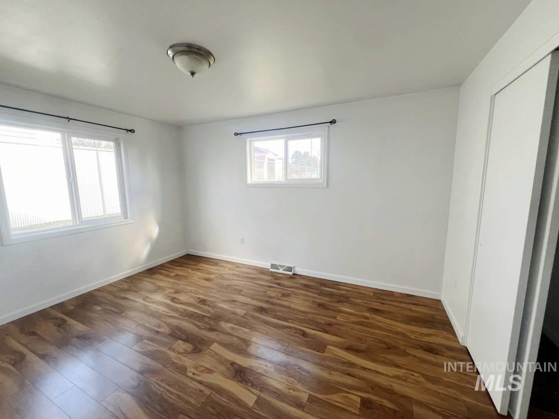 Empty room with dark wood-type flooring and healthy amount of natural light