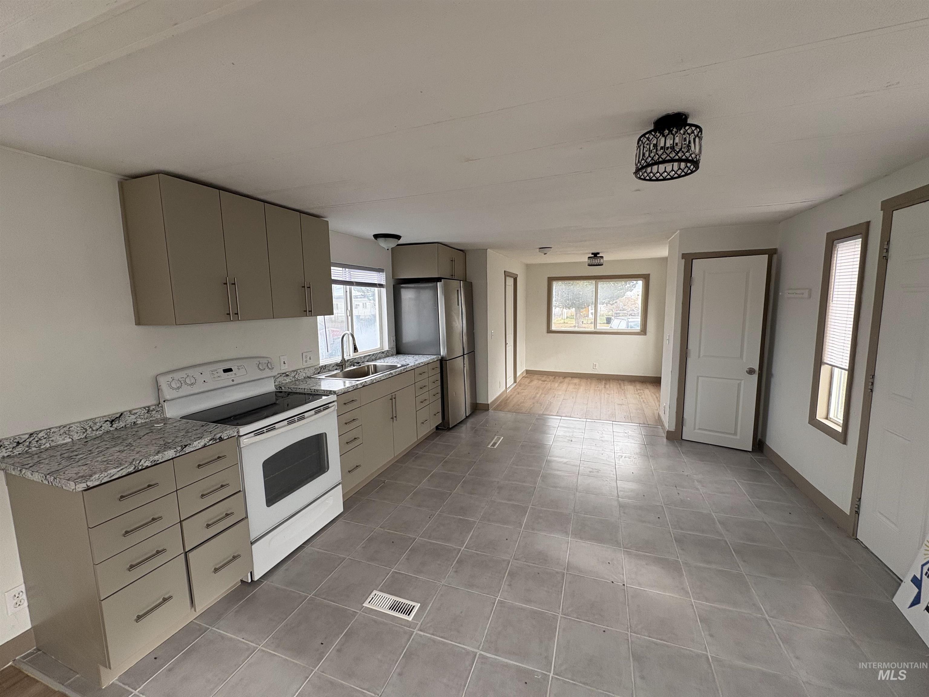 Kitchen with white range with electric cooktop, healthy amount of natural light, freestanding refrigerator, and gray cabinets
