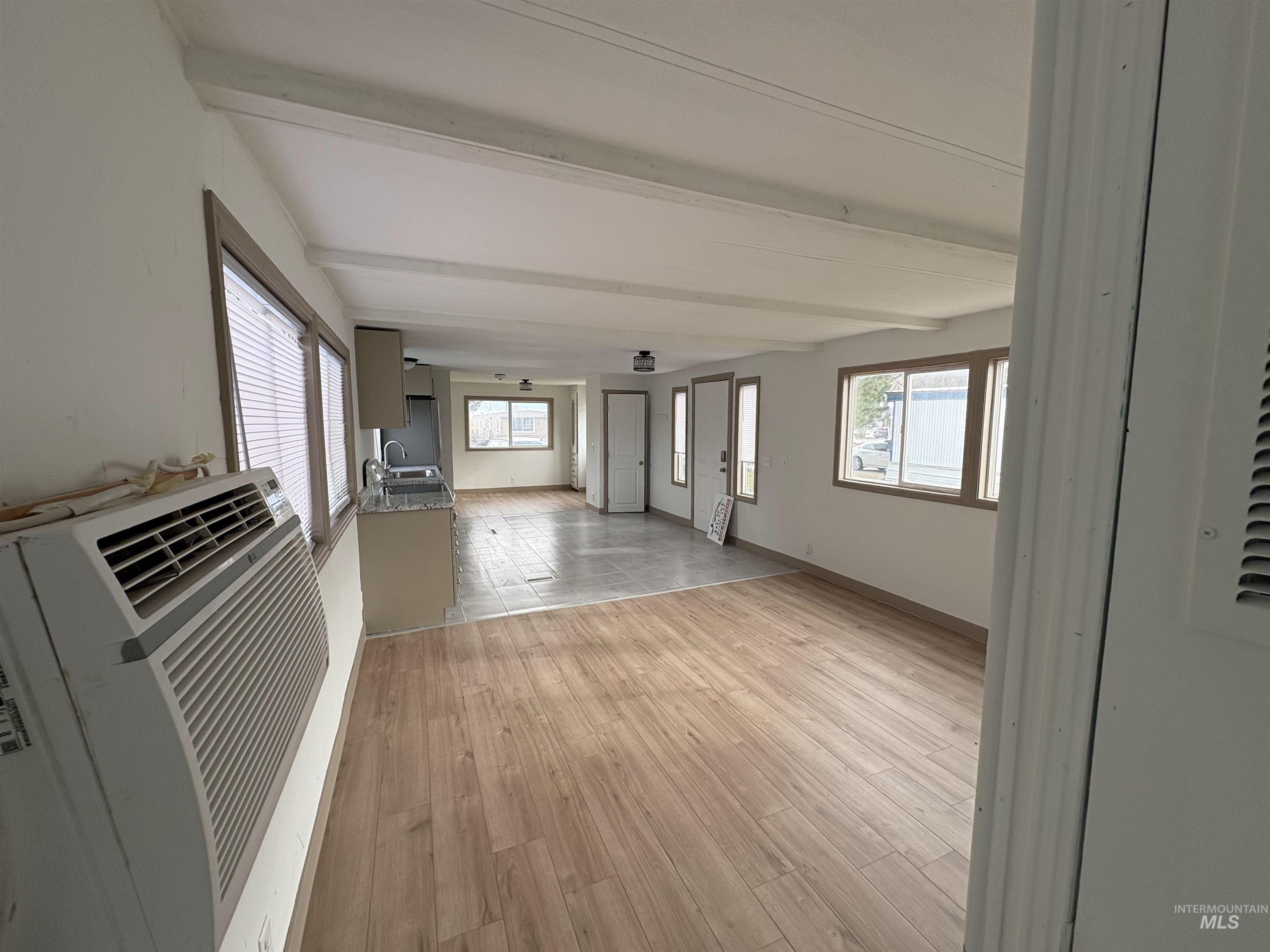 Corridor featuring beamed ceiling, light wood finished floors, and a wall mounted air conditioner
