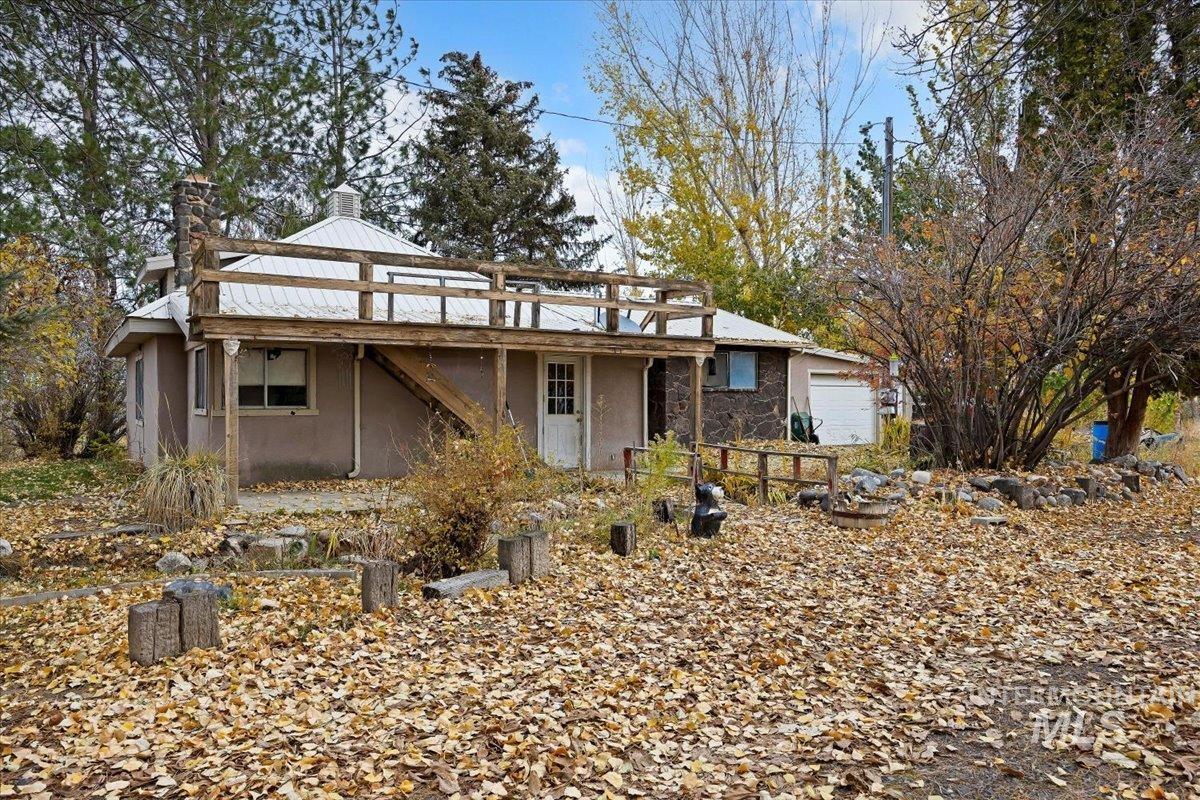 View of front of property with a chimney, stucco siding, a wooden deck, and stairs
