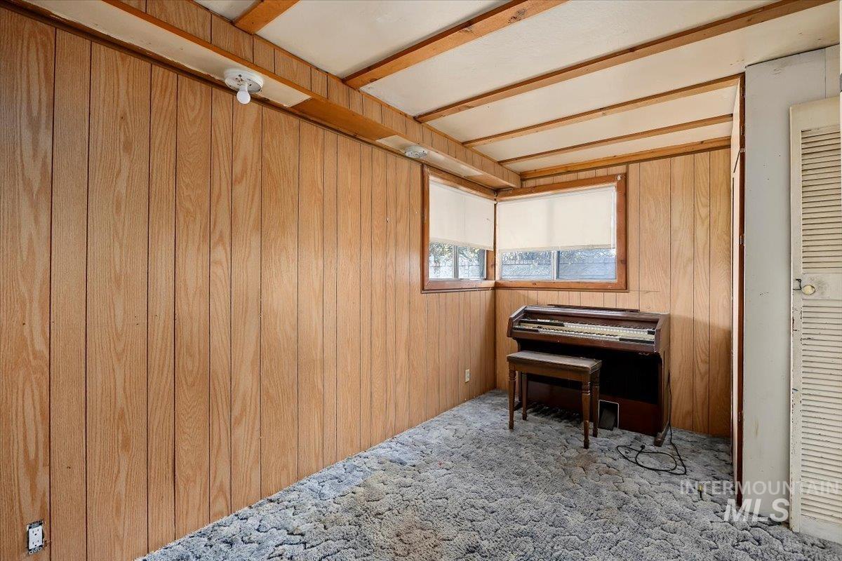 Living area with wood walls, carpet floors, and beam ceiling